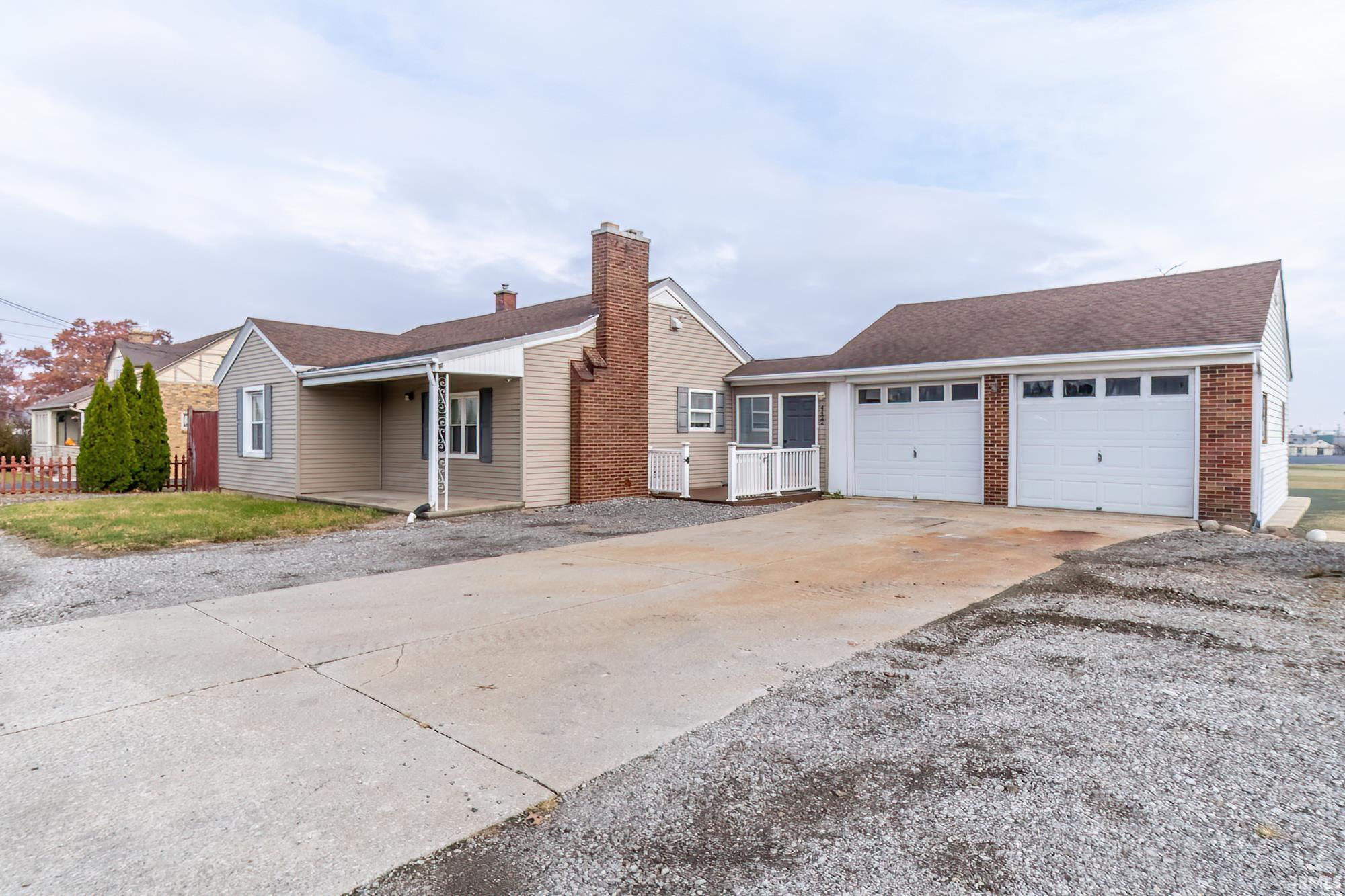 Ranch-style home with driveway, a chimney, a shingled roof, a garage, and brick siding