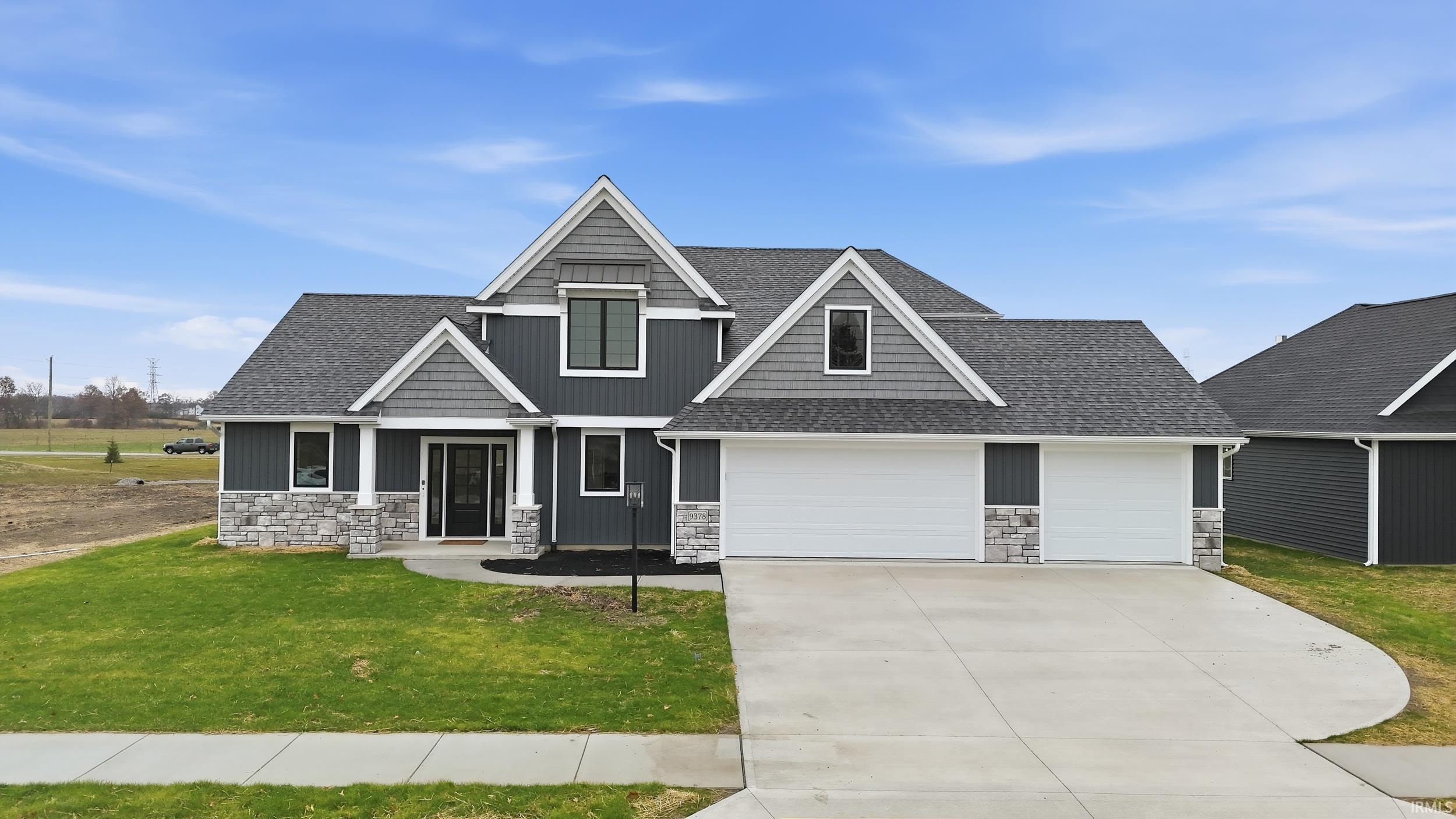 Craftsman-style home featuring stone siding, roof with shingles, a front lawn, concrete driveway, and board and batten siding
