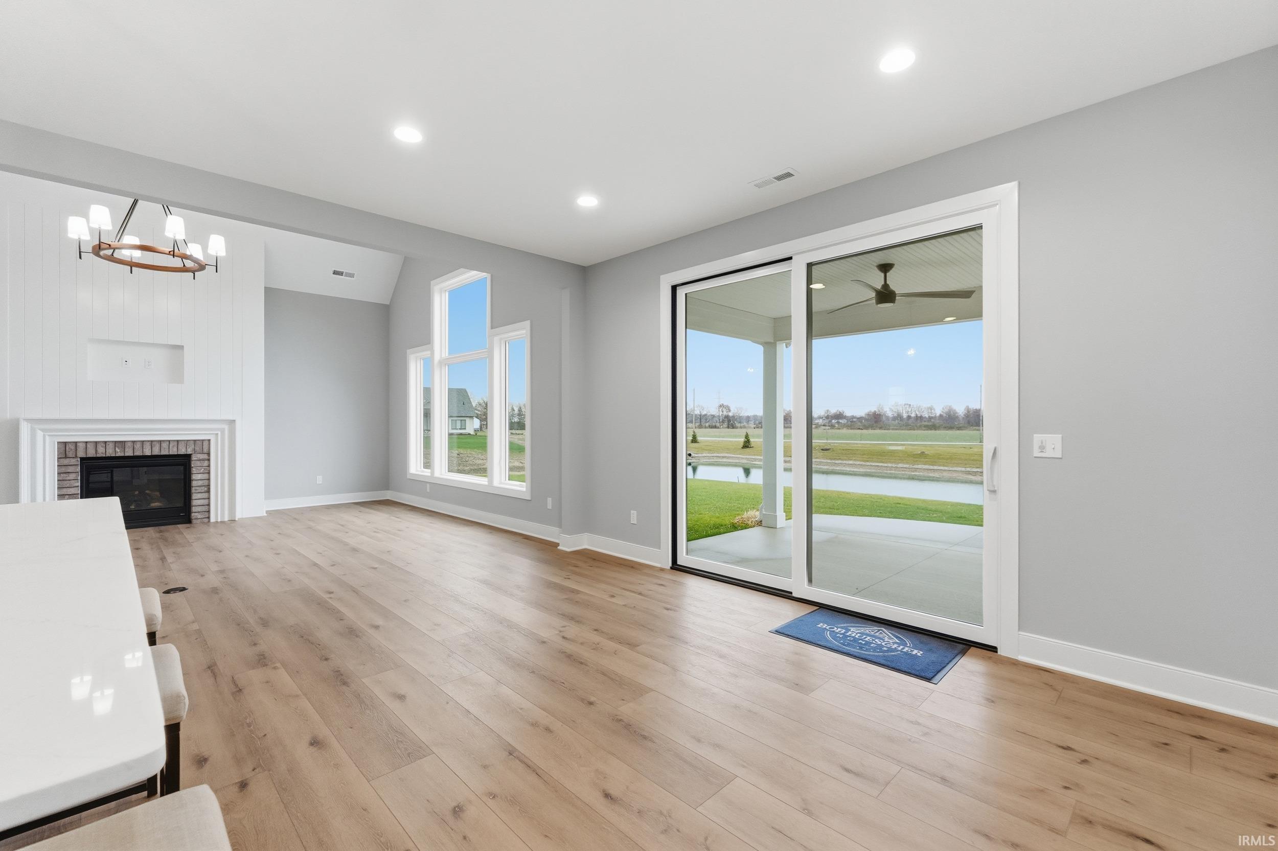 Unfurnished living room with light wood-type flooring, a brick fireplace, recessed lighting, and a chandelier
