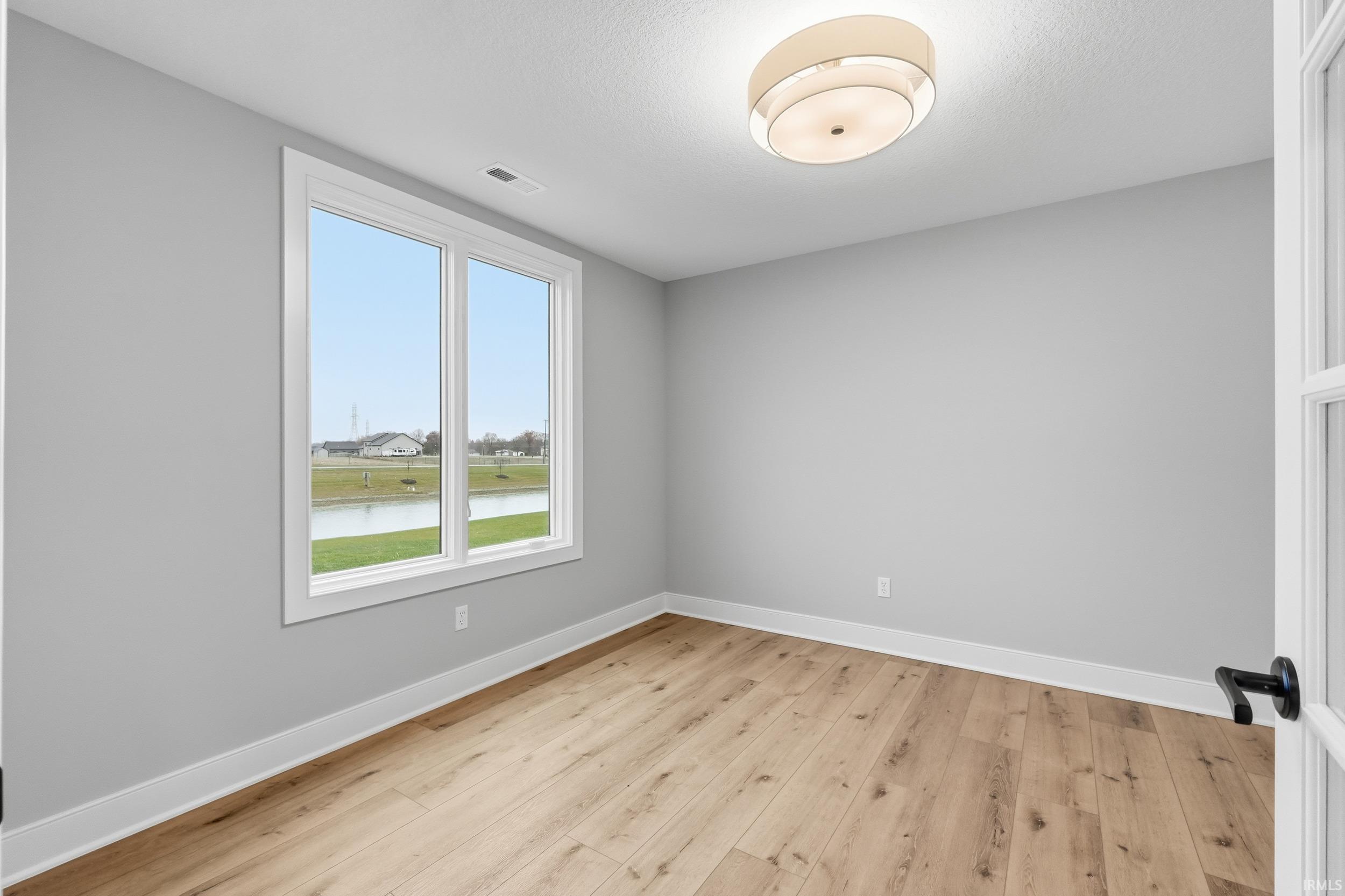Spare room with a water view and light wood finished floors