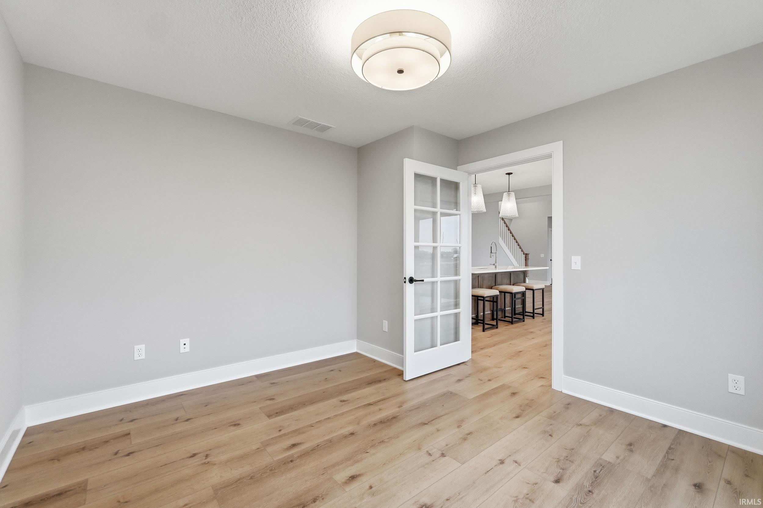 Empty room featuring light wood-type flooring and a textured ceiling