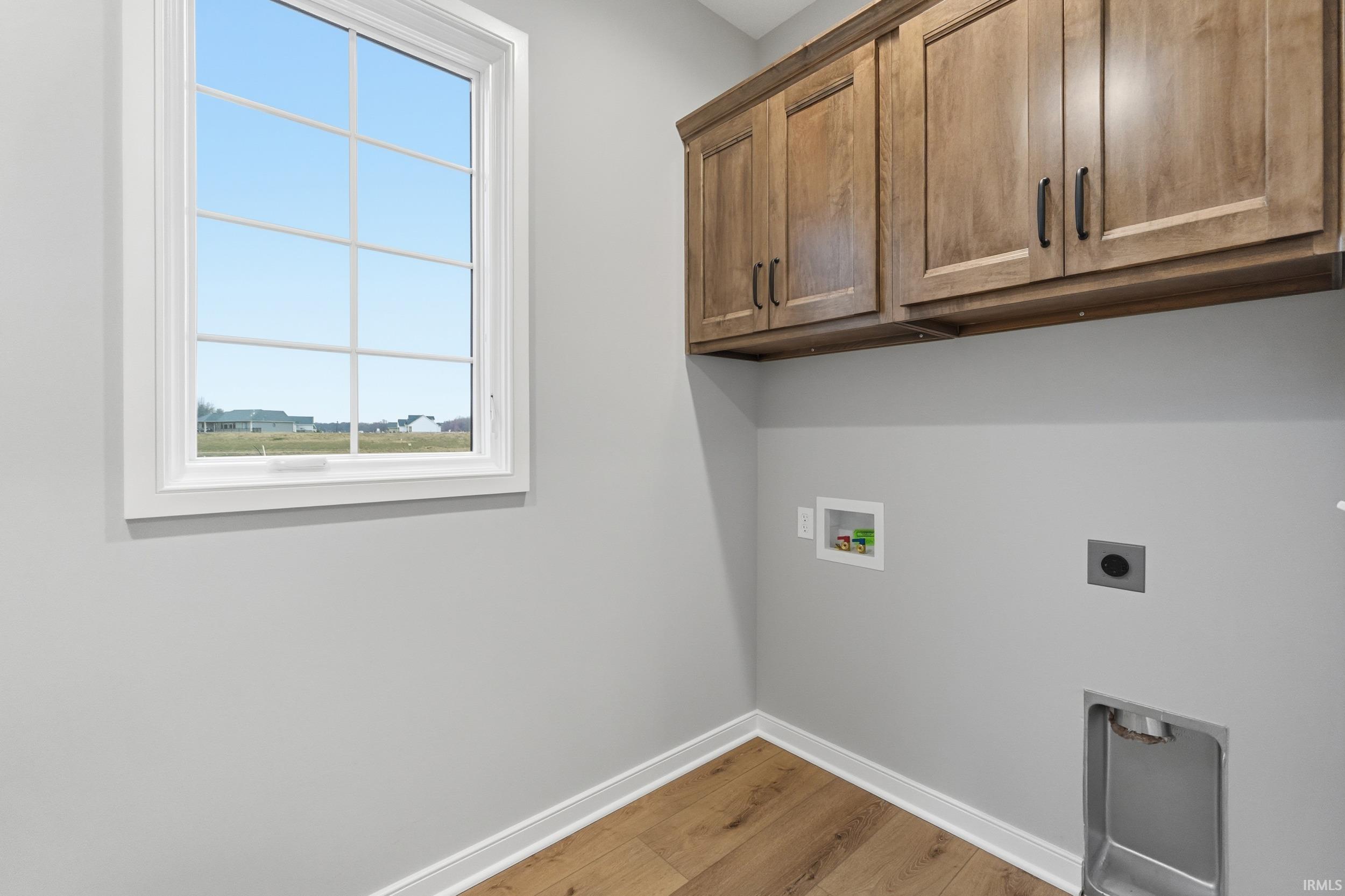 Washroom with light wood-style floors, hookup for a washing machine, cabinet space, and electric dryer hookup