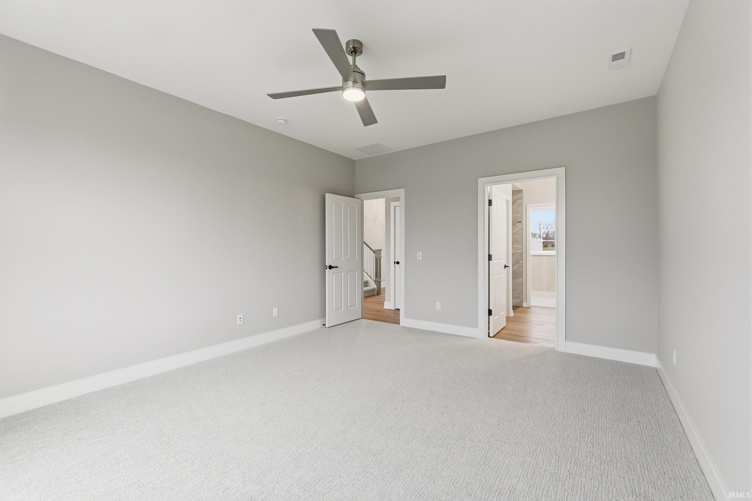 Unfurnished bedroom featuring carpet floors, ceiling fan, and connected bathroom