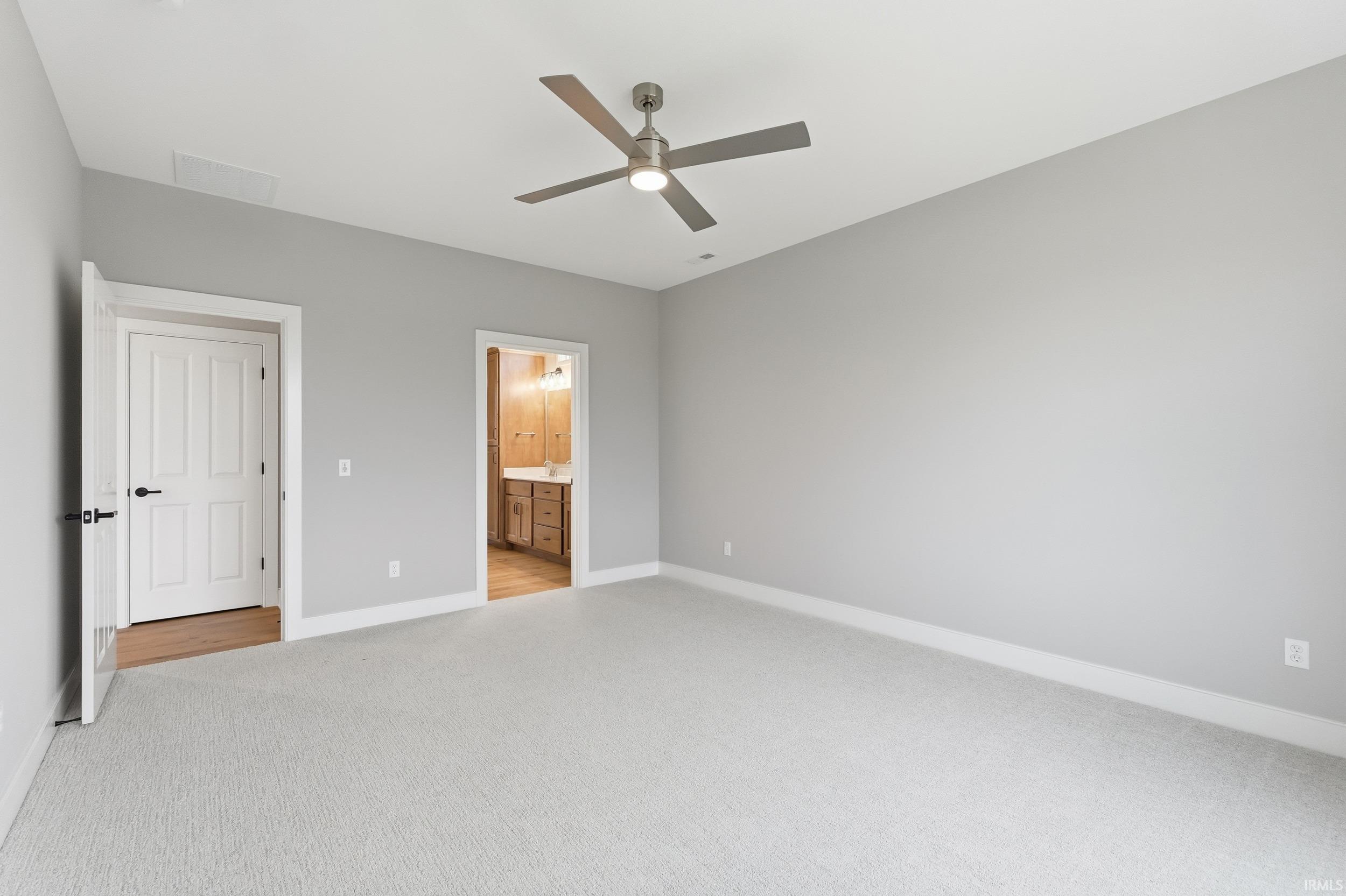 Unfurnished bedroom with light carpet, a ceiling fan, and ensuite bath