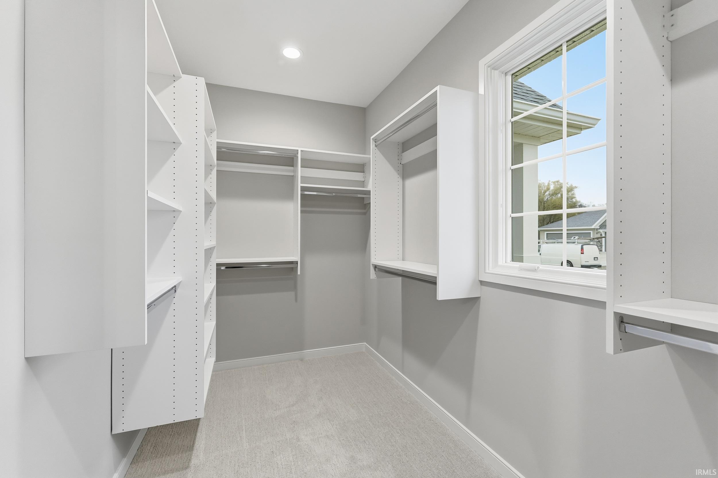 Spacious closet featuring light colored carpet