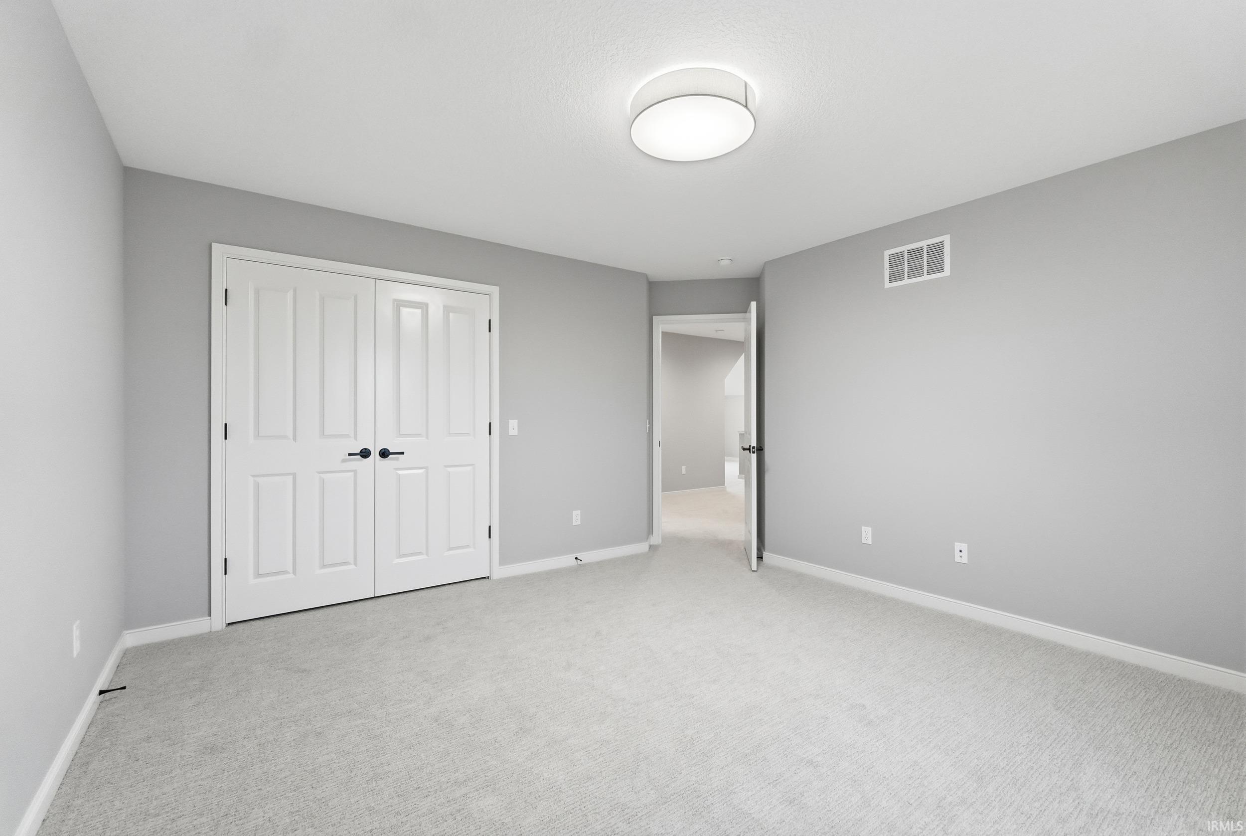 Unfurnished bedroom with light colored carpet and a closet