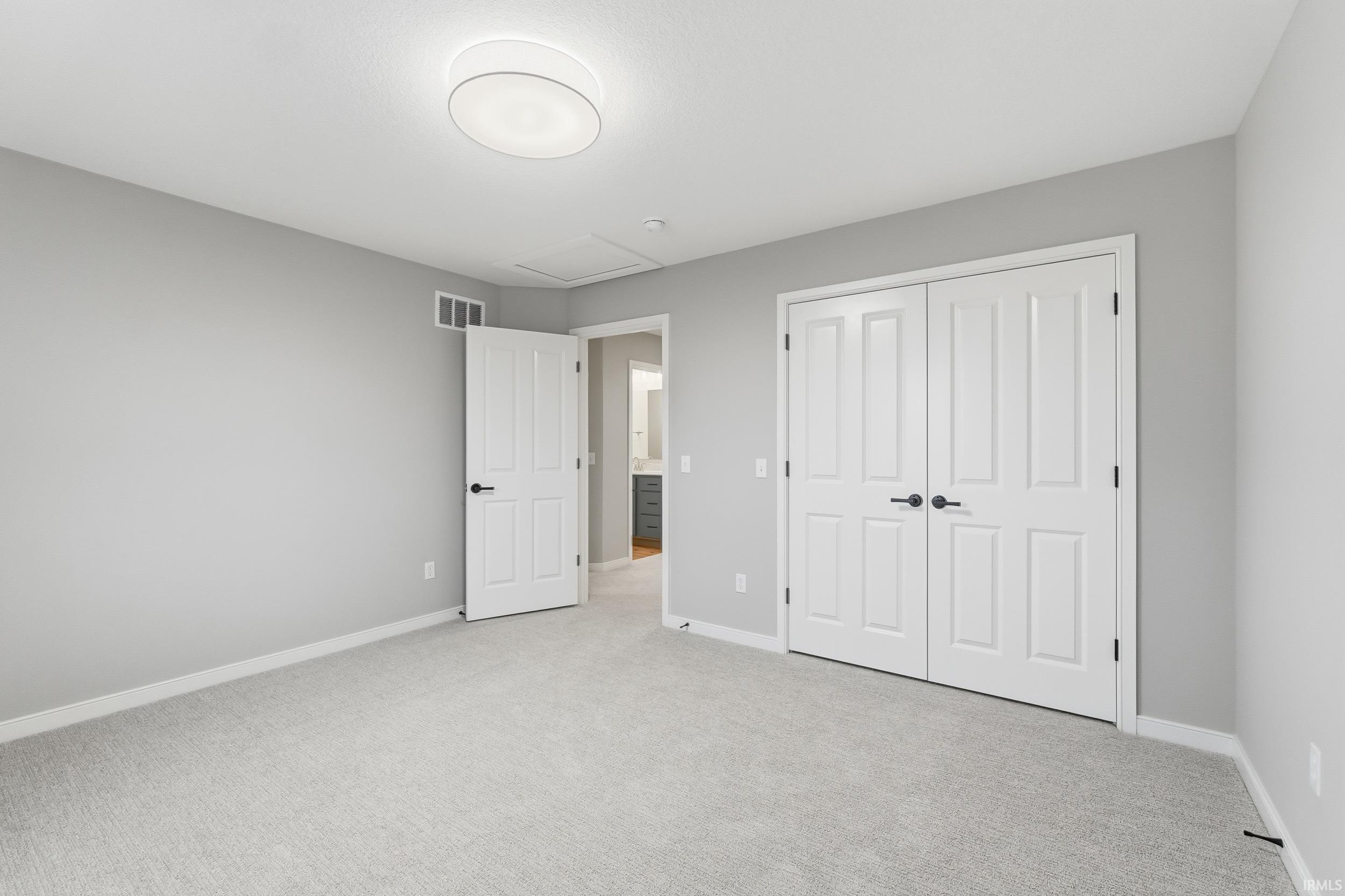Unfurnished bedroom featuring attic access, carpet flooring, and a closet