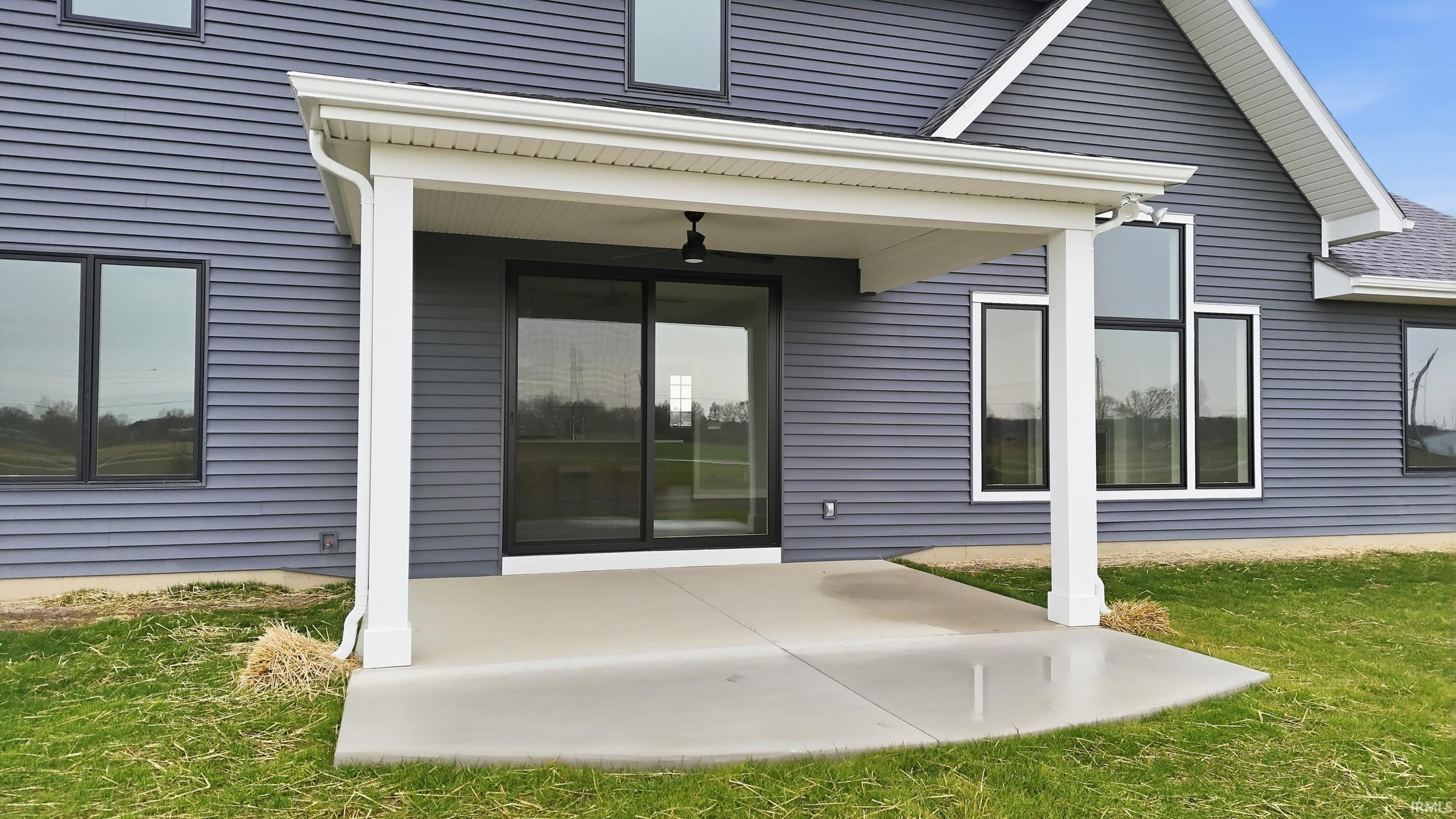 View of exterior entry featuring a patio, ceiling fan, and a lawn