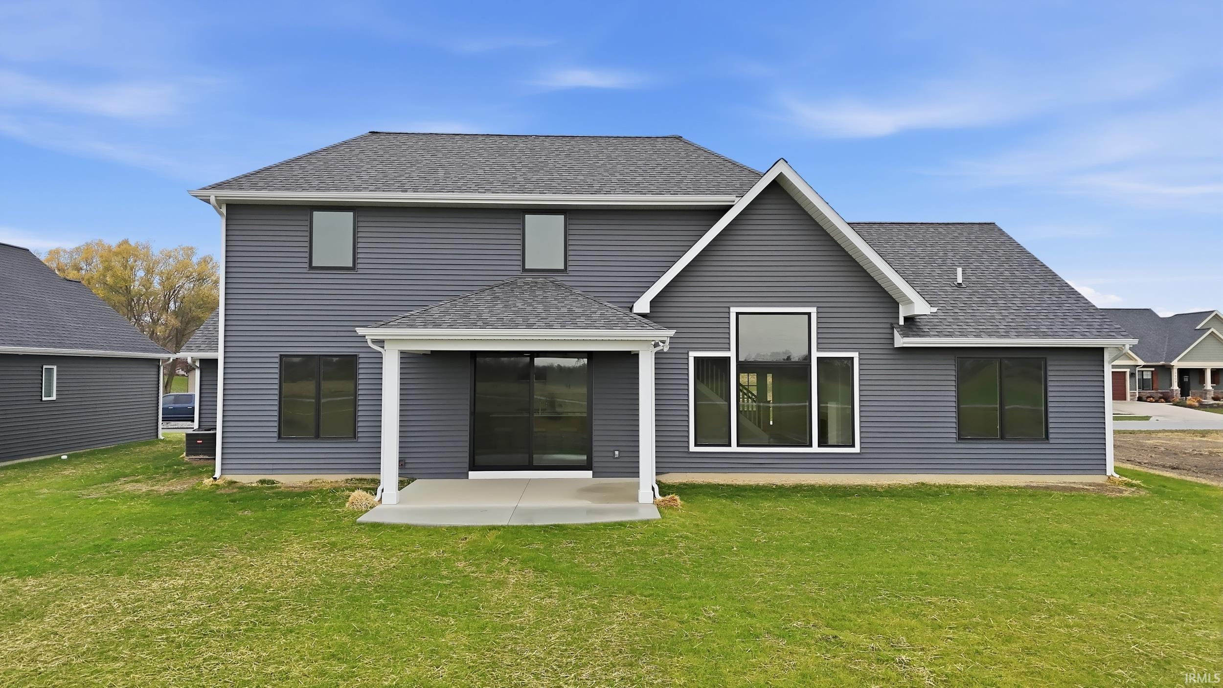 Rear view of property with a shingled roof and a lawn