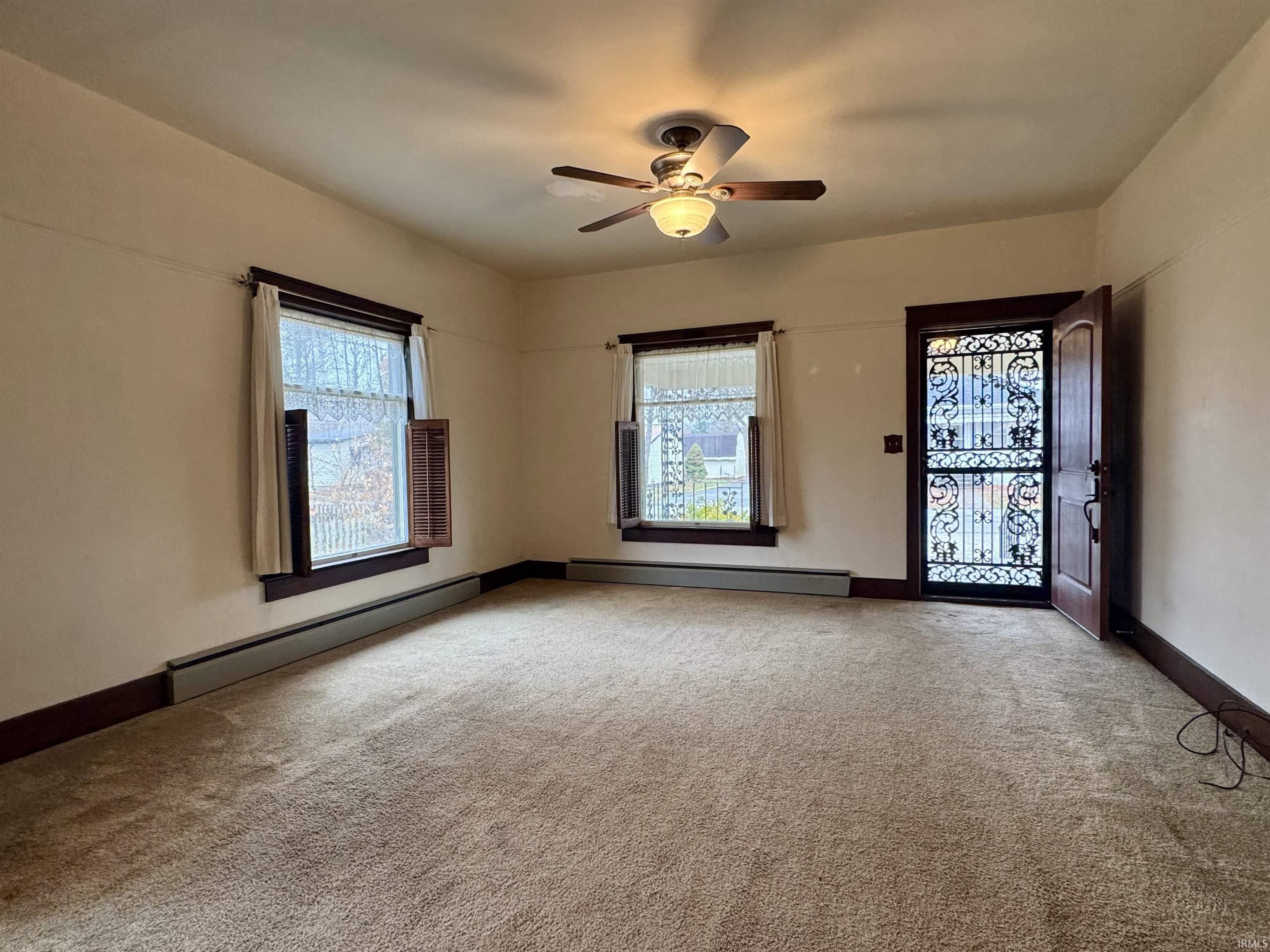 Unfurnished room with a baseboard radiator, light carpet, and a ceiling fan