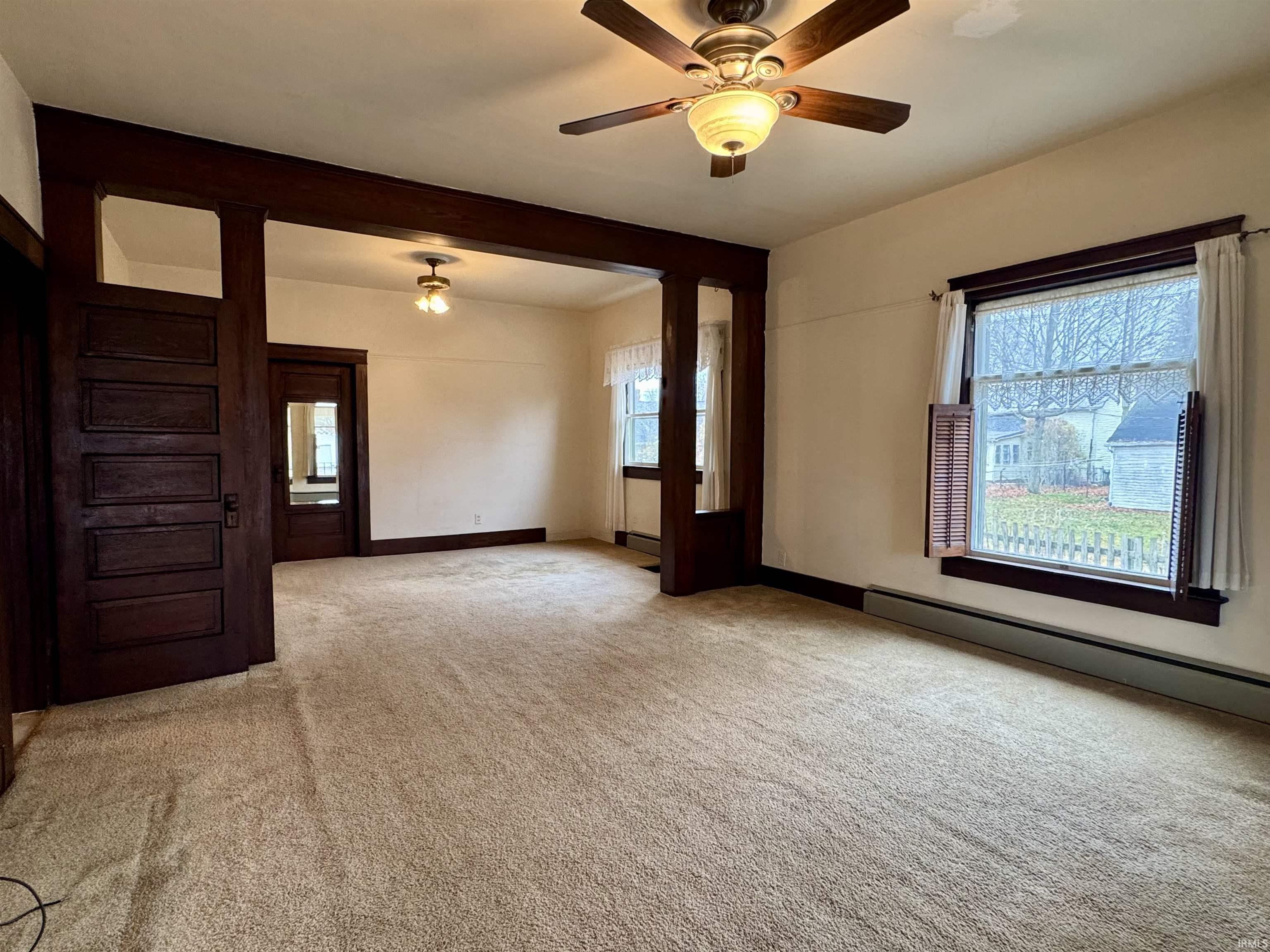 Spare room featuring healthy amount of natural light, light colored carpet, a ceiling fan, and a baseboard heating unit