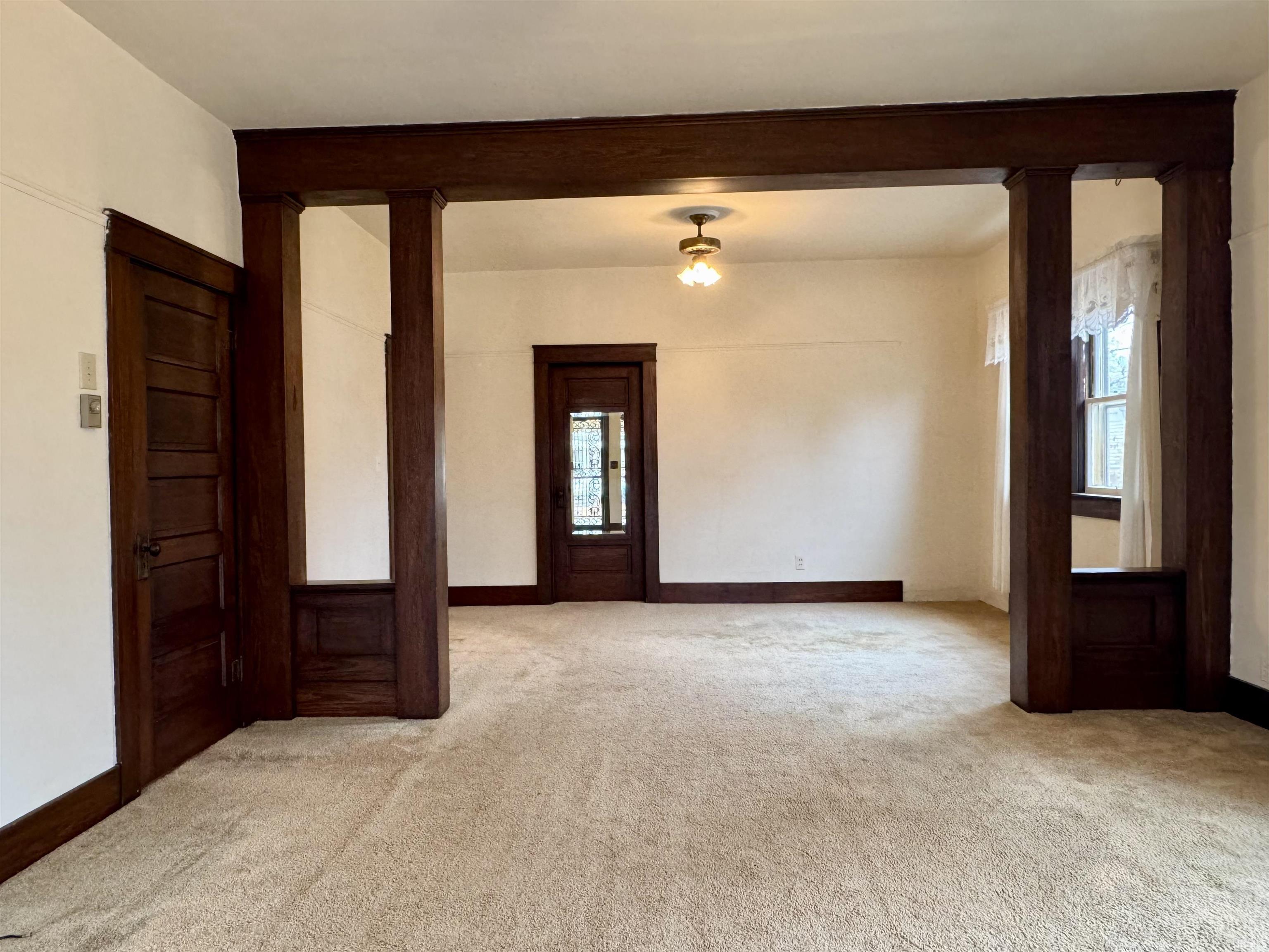 Unfurnished room featuring ornate columns and light carpet