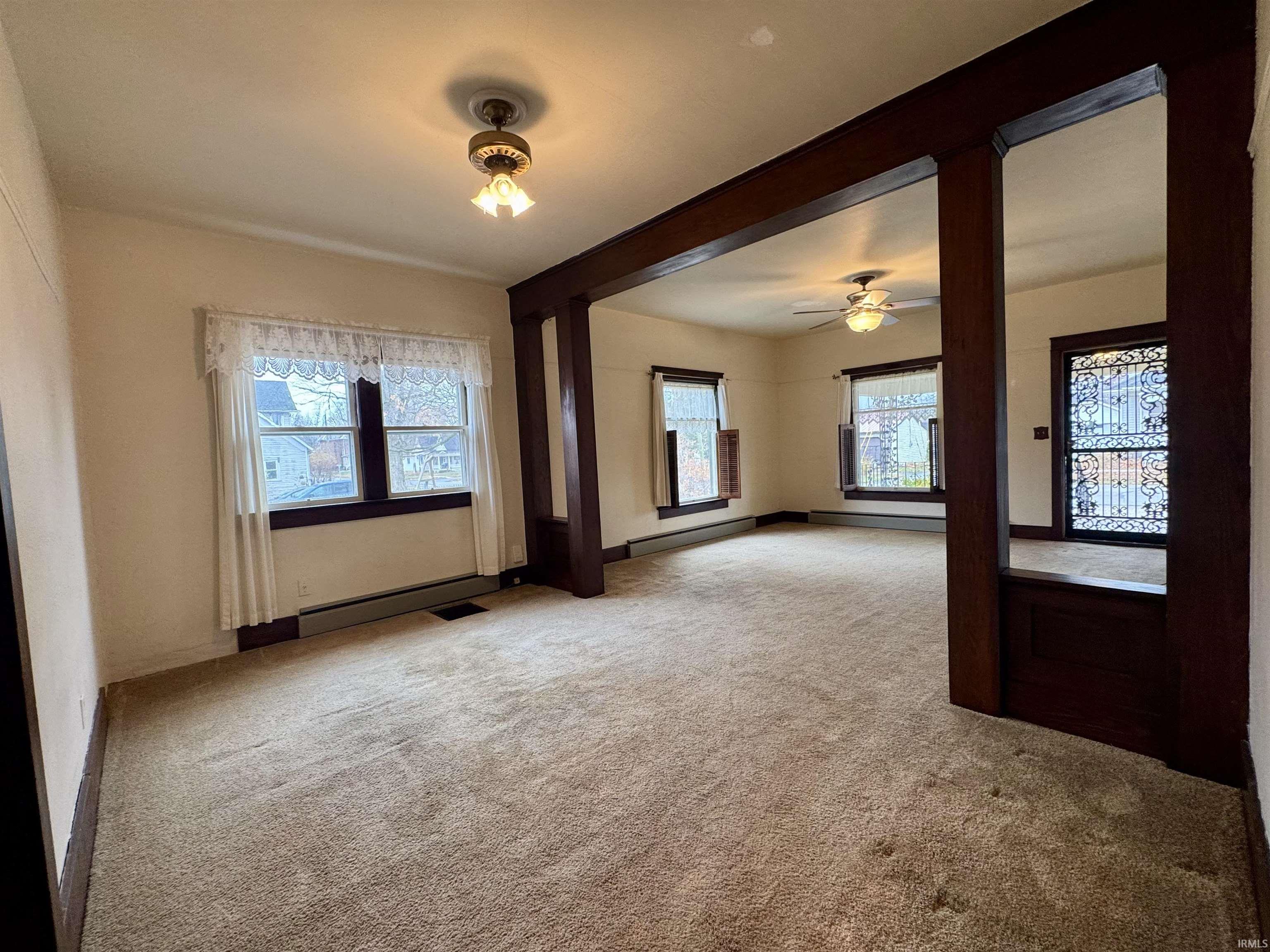 Empty room with light carpet, ceiling fan, and a baseboard radiator