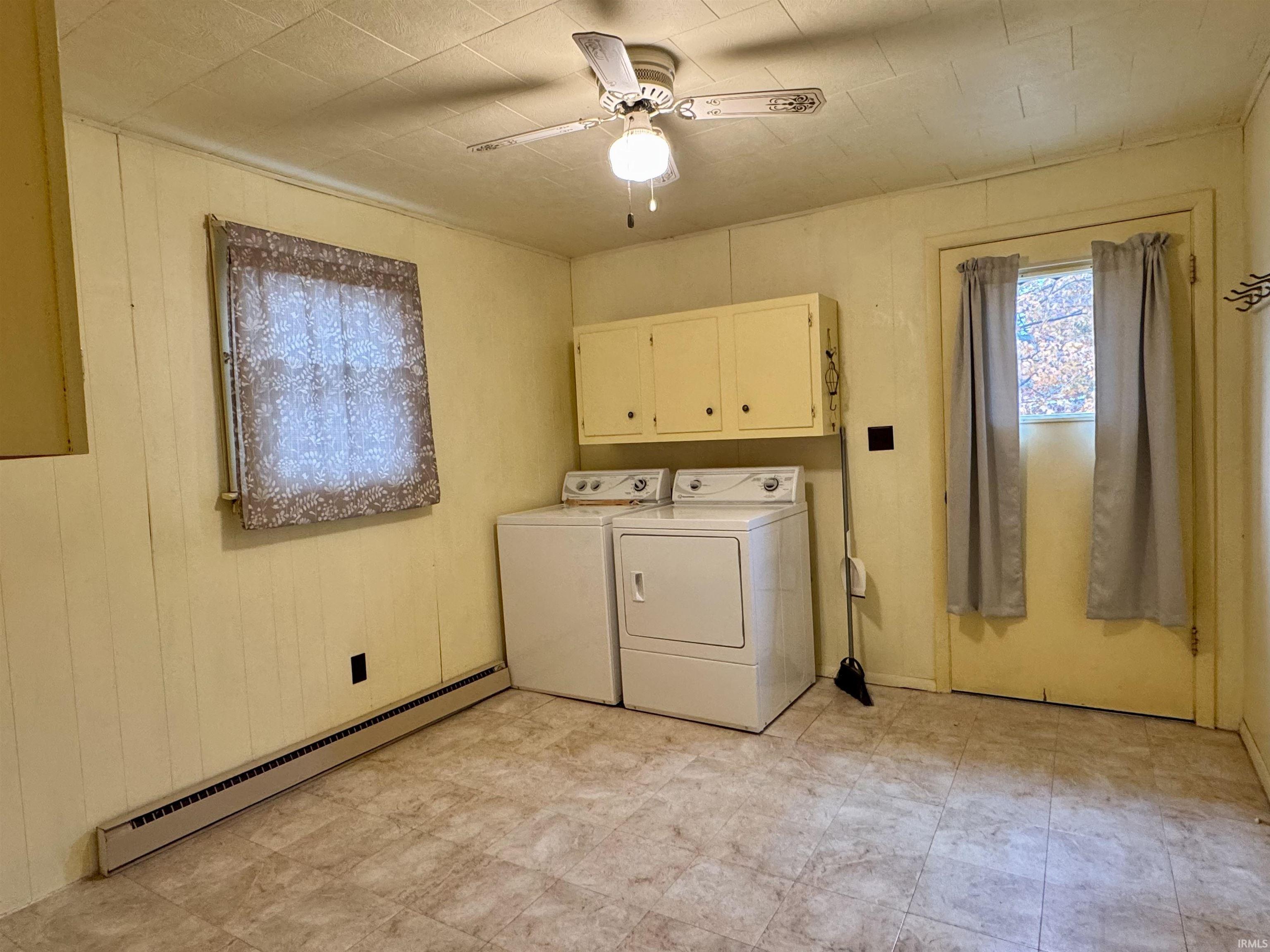 Laundry area featuring a baseboard heating unit, light floors, cabinet space, a ceiling fan, and washer and clothes dryer