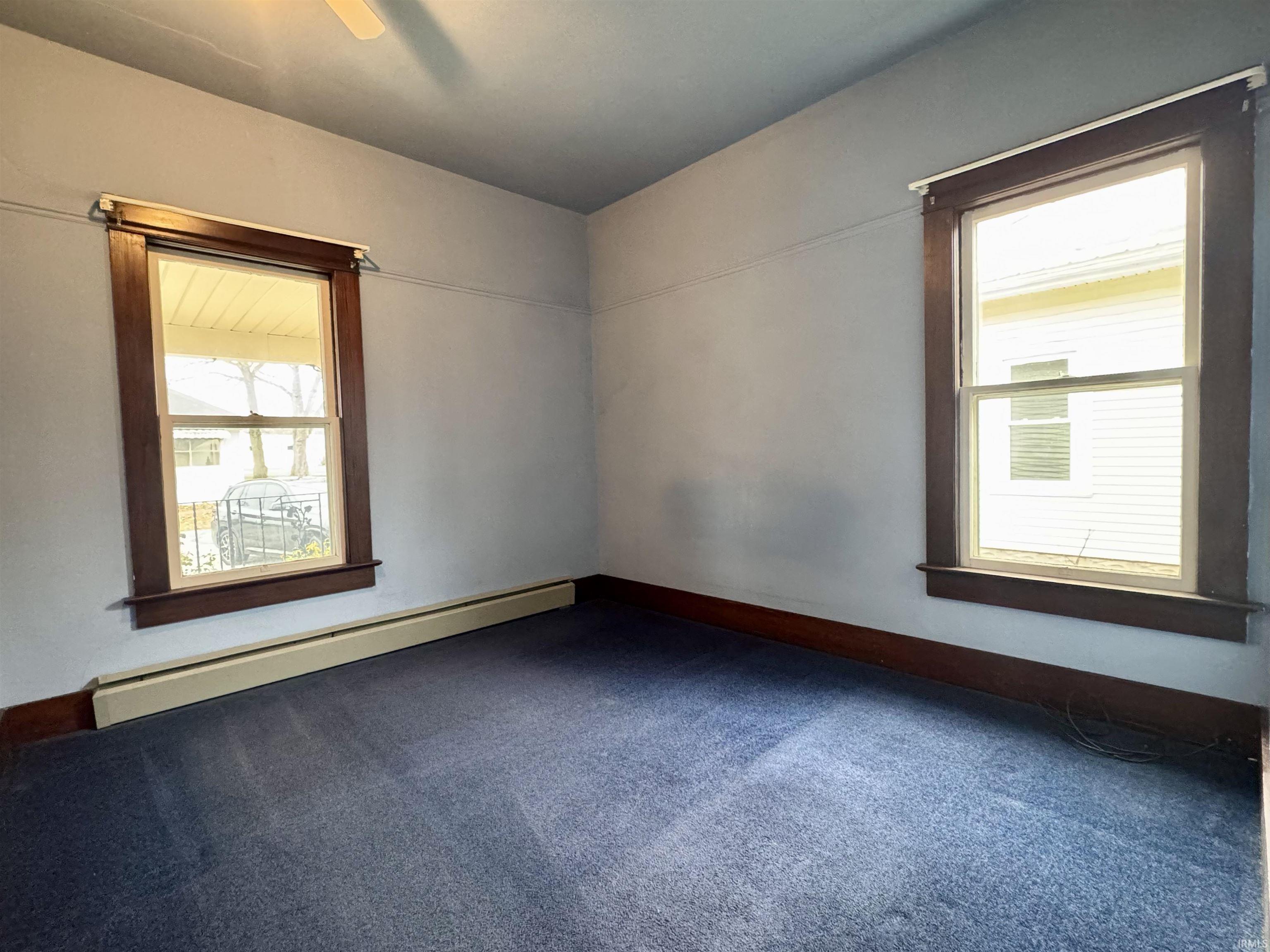 Carpeted spare room featuring baseboard heating and ceiling fan
