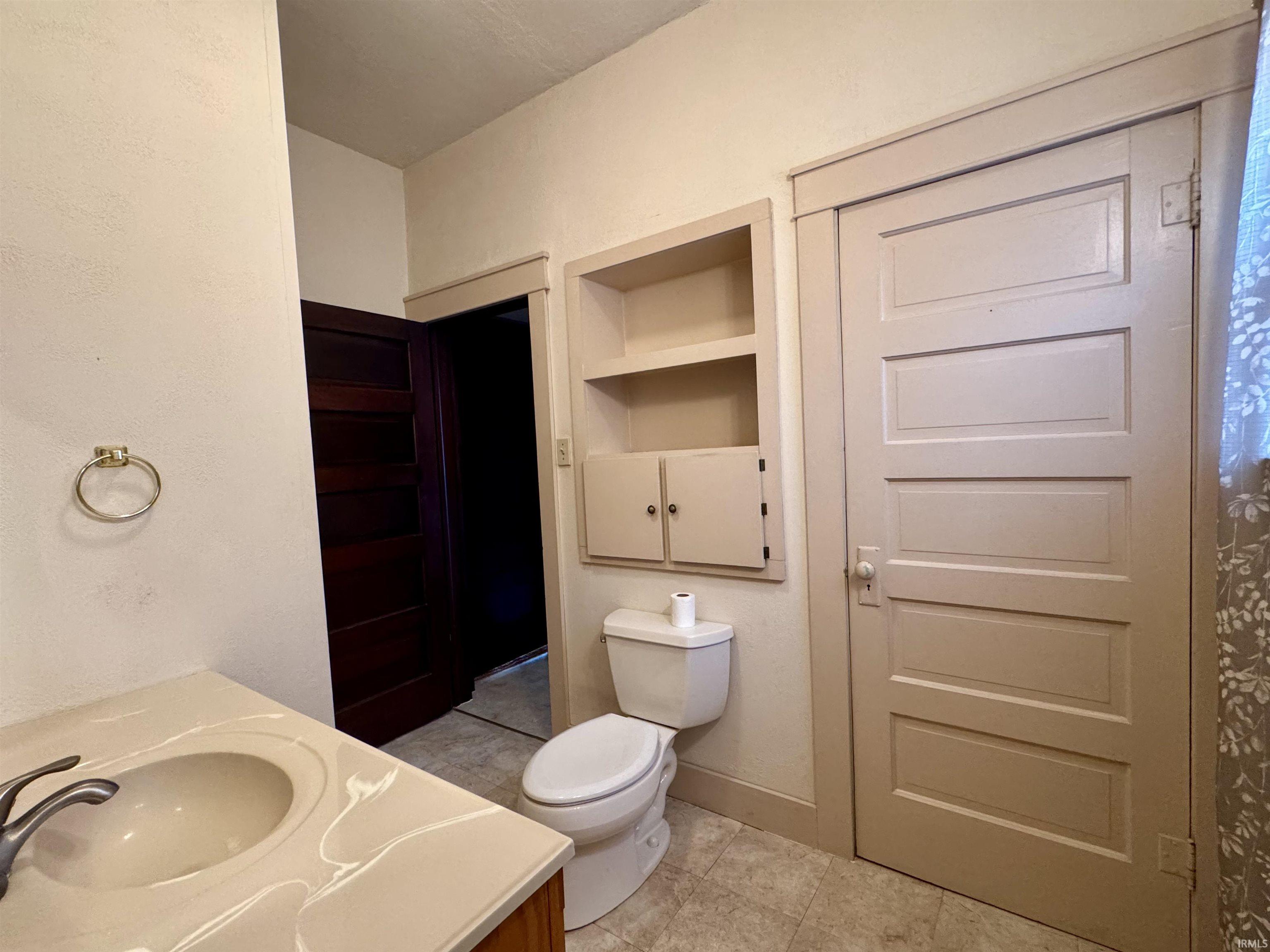 Bathroom featuring vanity, built in shelves, light tile patterned floors, and a textured wall