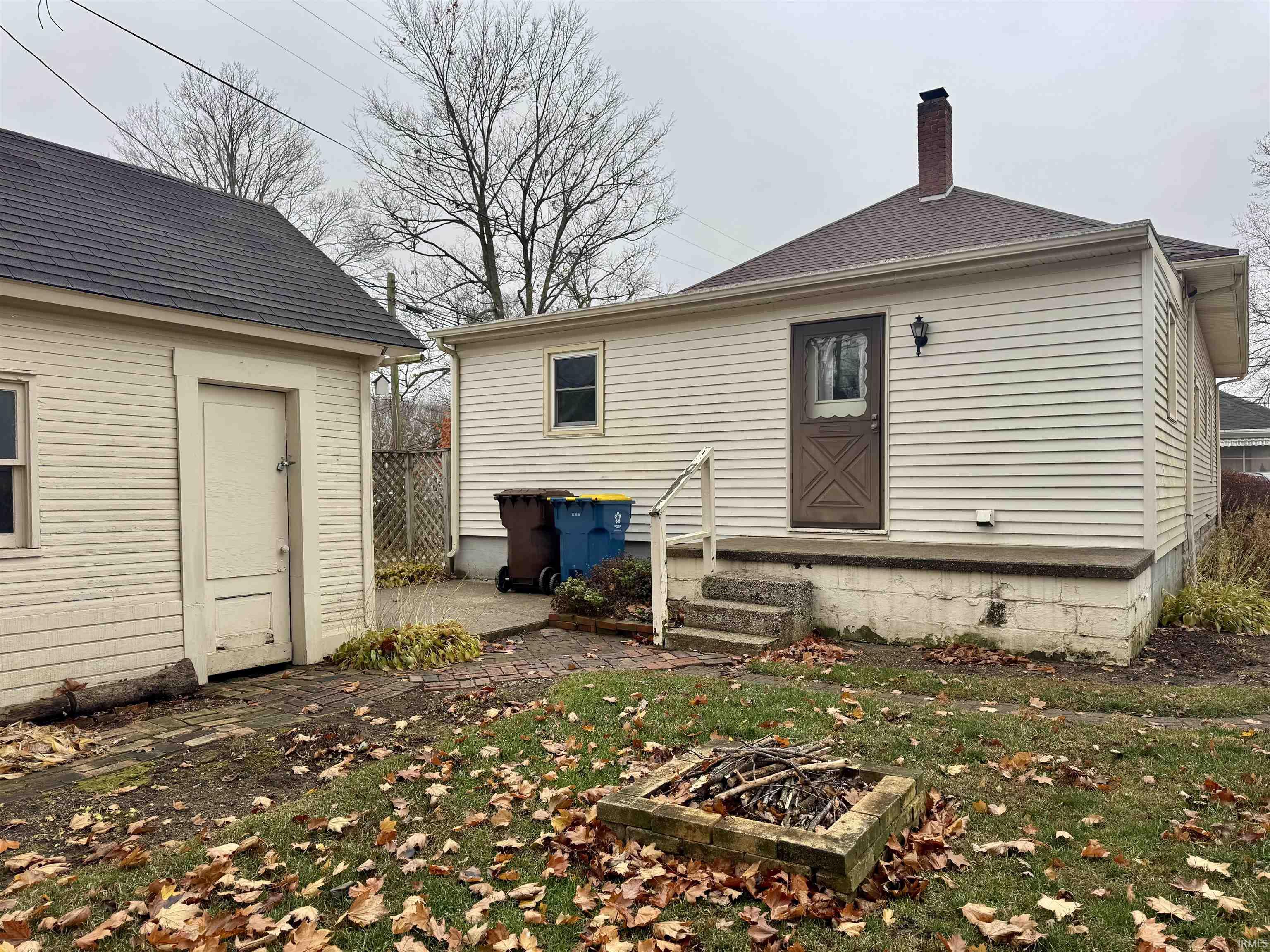 Rear view of house with a chimney, an outdoor fire pit, a patio, and an outbuilding