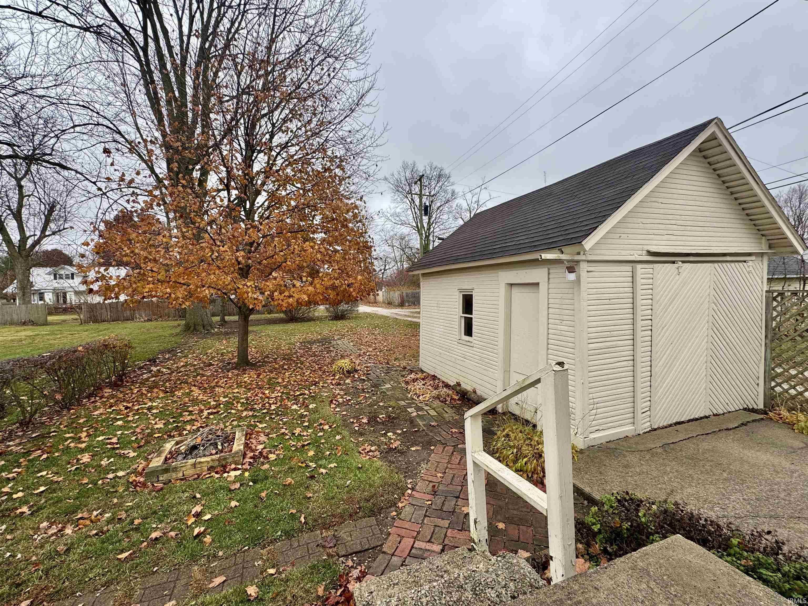 View of property exterior featuring an outdoor fire pit, roof with shingles, and a storage shed