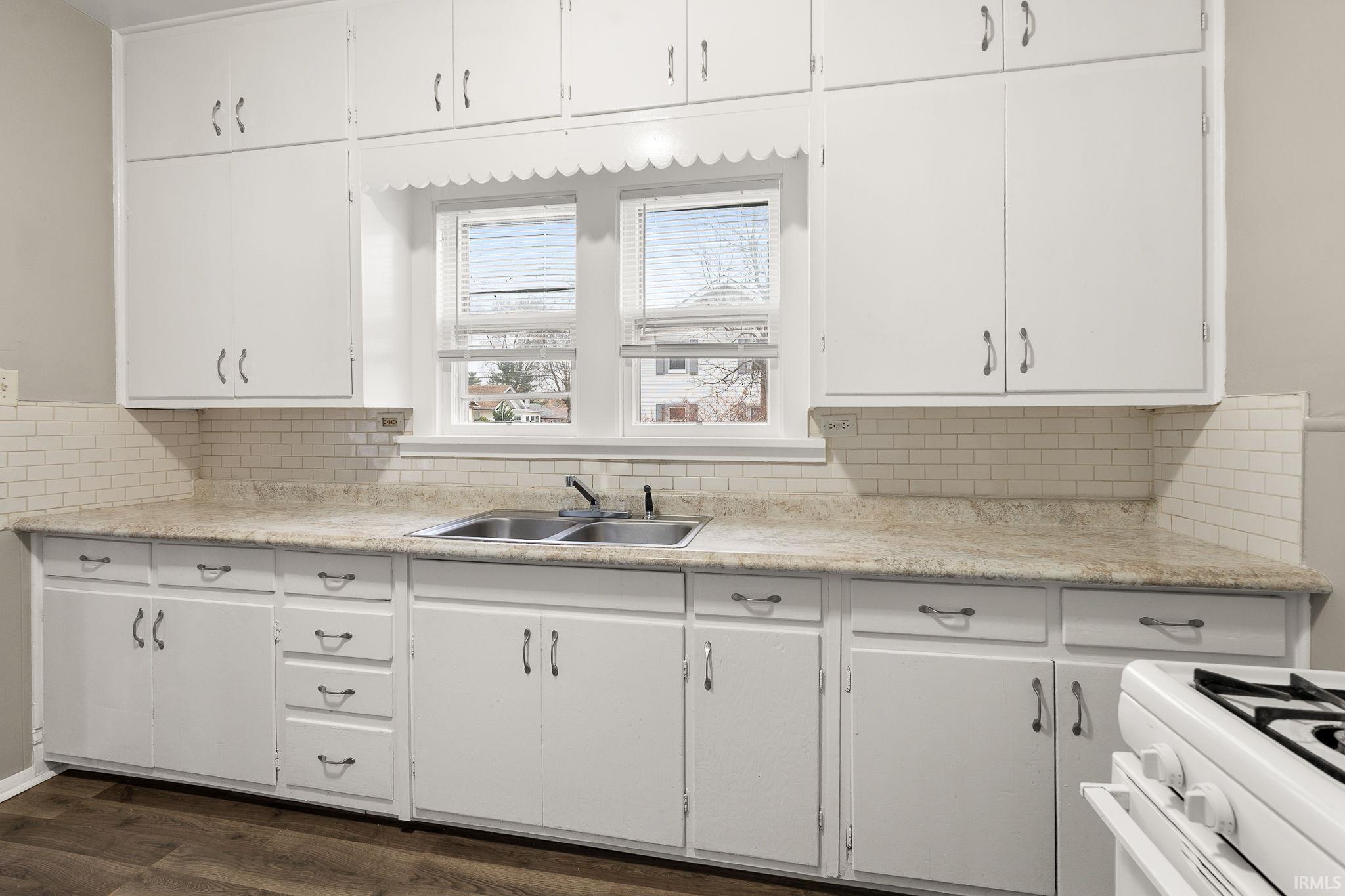 Kitchen with light countertops, gas range gas stove, and white cabinets