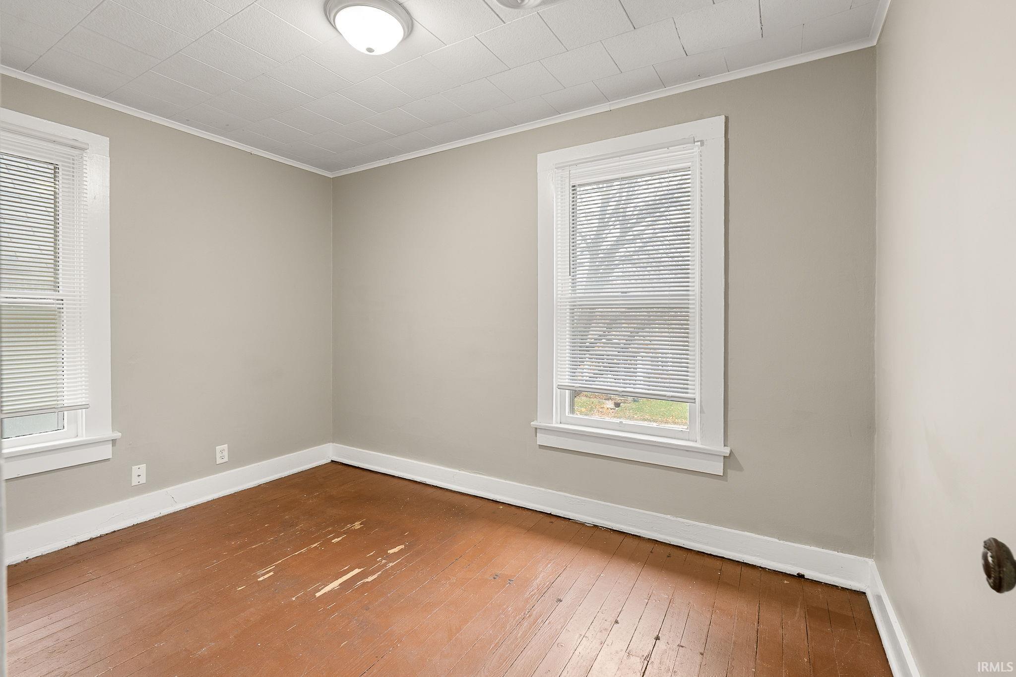 Unfurnished room with hardwood / wood-style floors, plenty of natural light, and crown molding