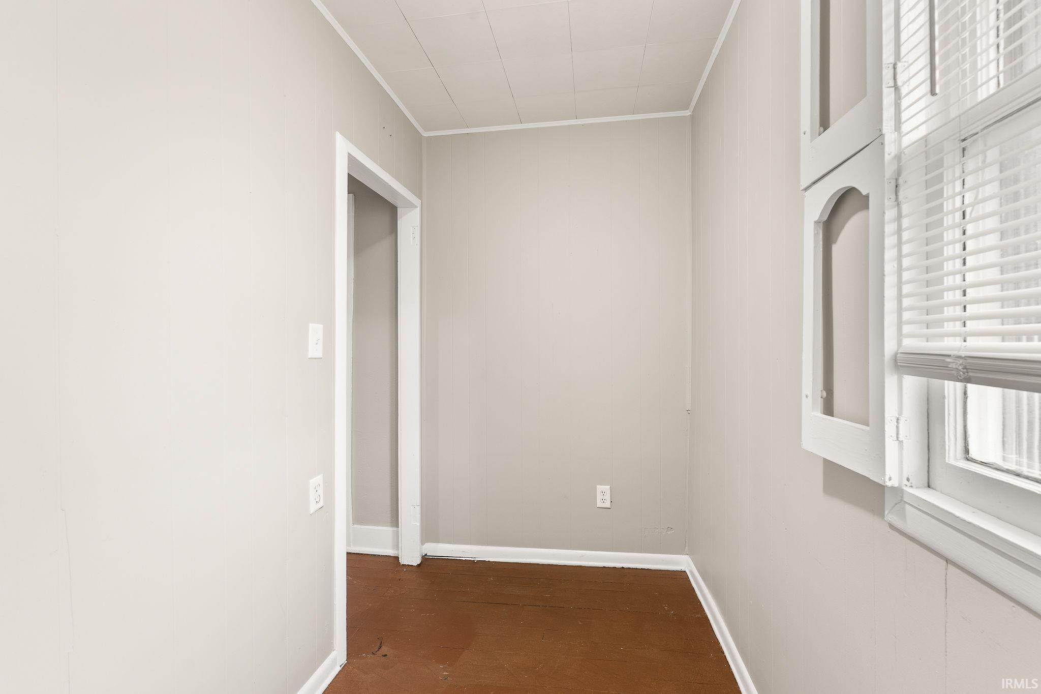 Unfurnished room with crown molding and dark wood-style floors
