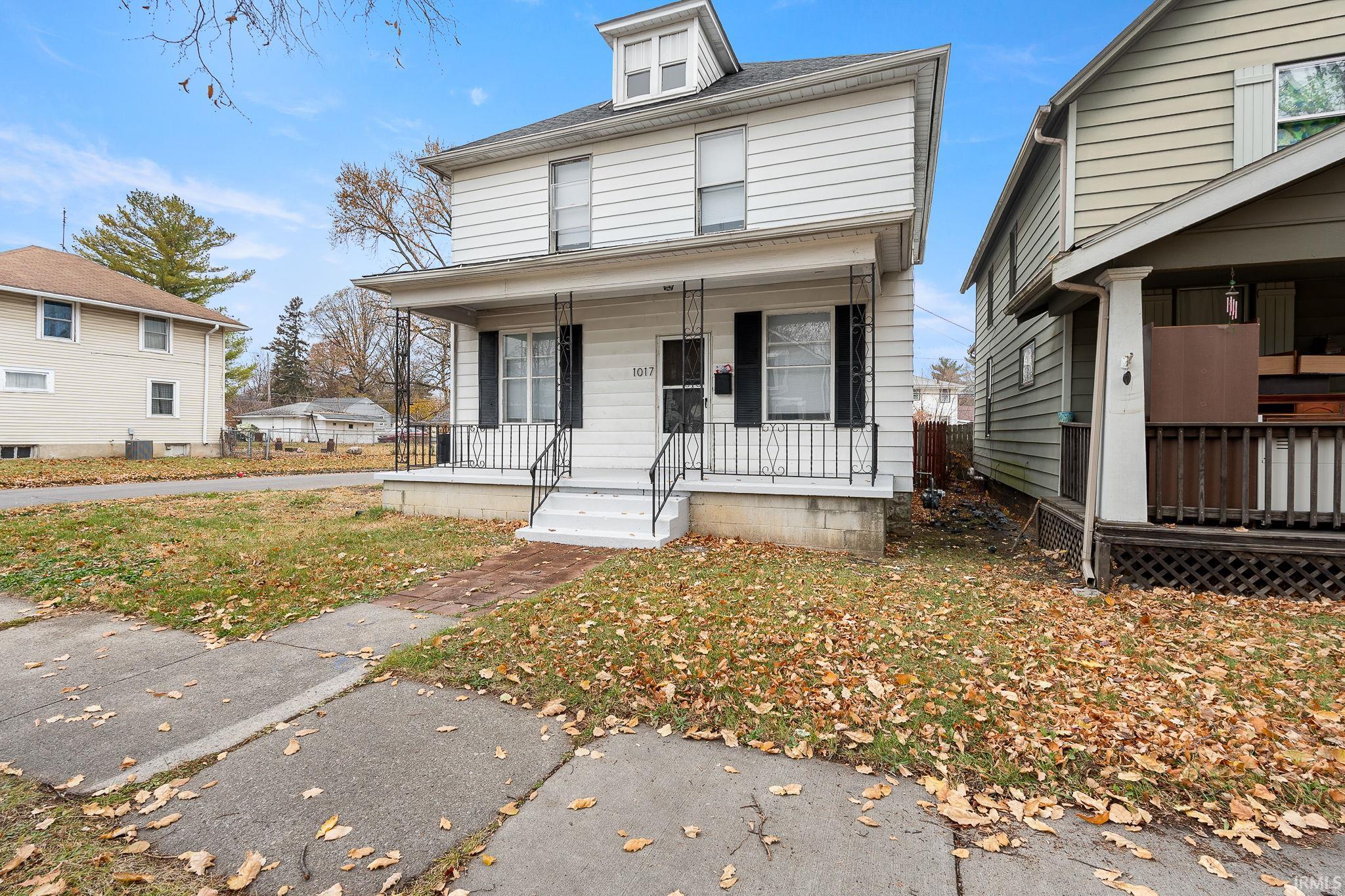 American foursquare style home with covered porch and a front lawn