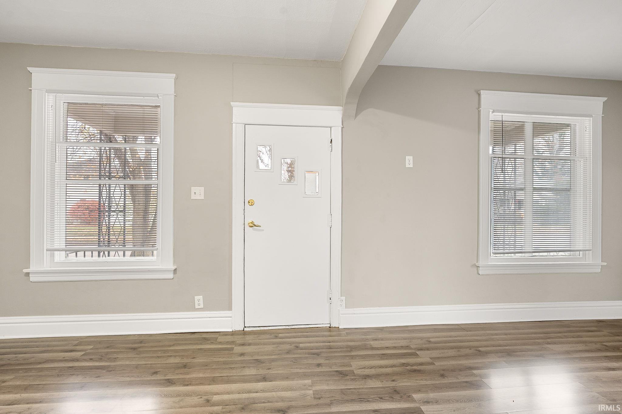 Foyer with arched walkways, wood finished floors, and beam ceiling
