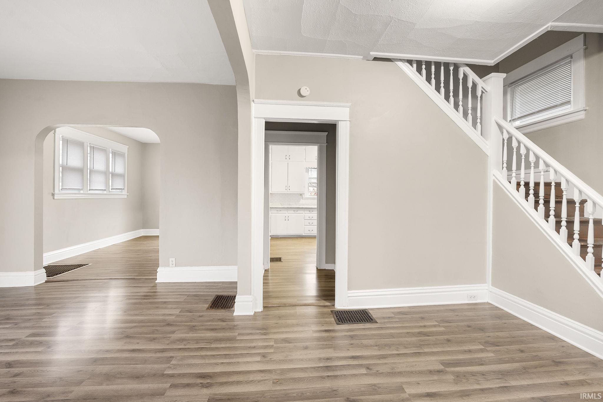 Stairway with wood finished floors, arched walkways, and plenty of natural light