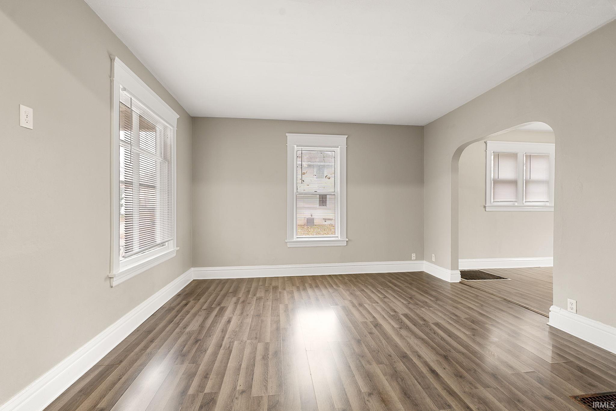 Spare room with arched walkways and wood finished floors