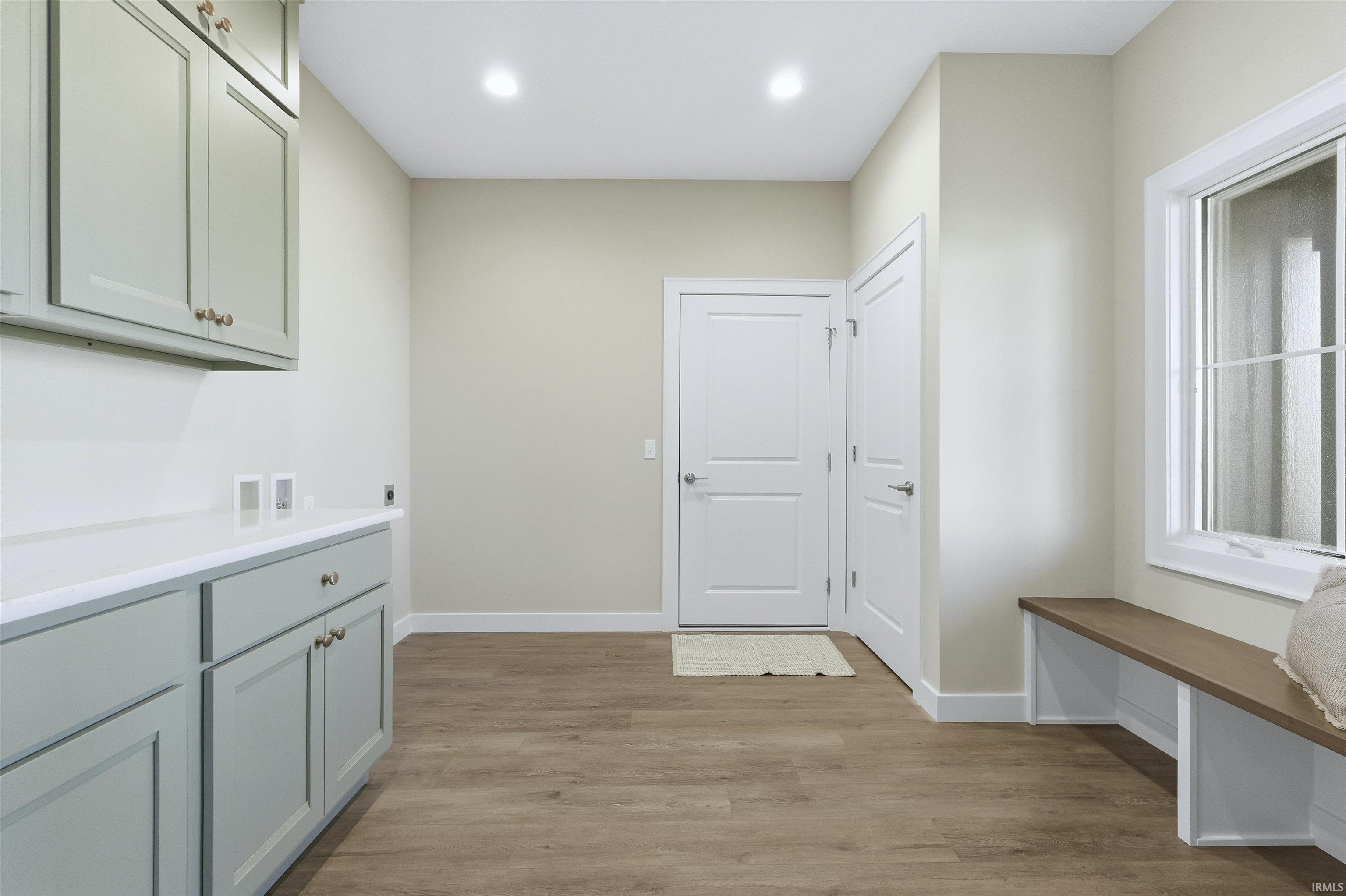 Laundry area with light wood-style floors, cabinet space, hookup for a washing machine, electric dryer hookup, and recessed lighting