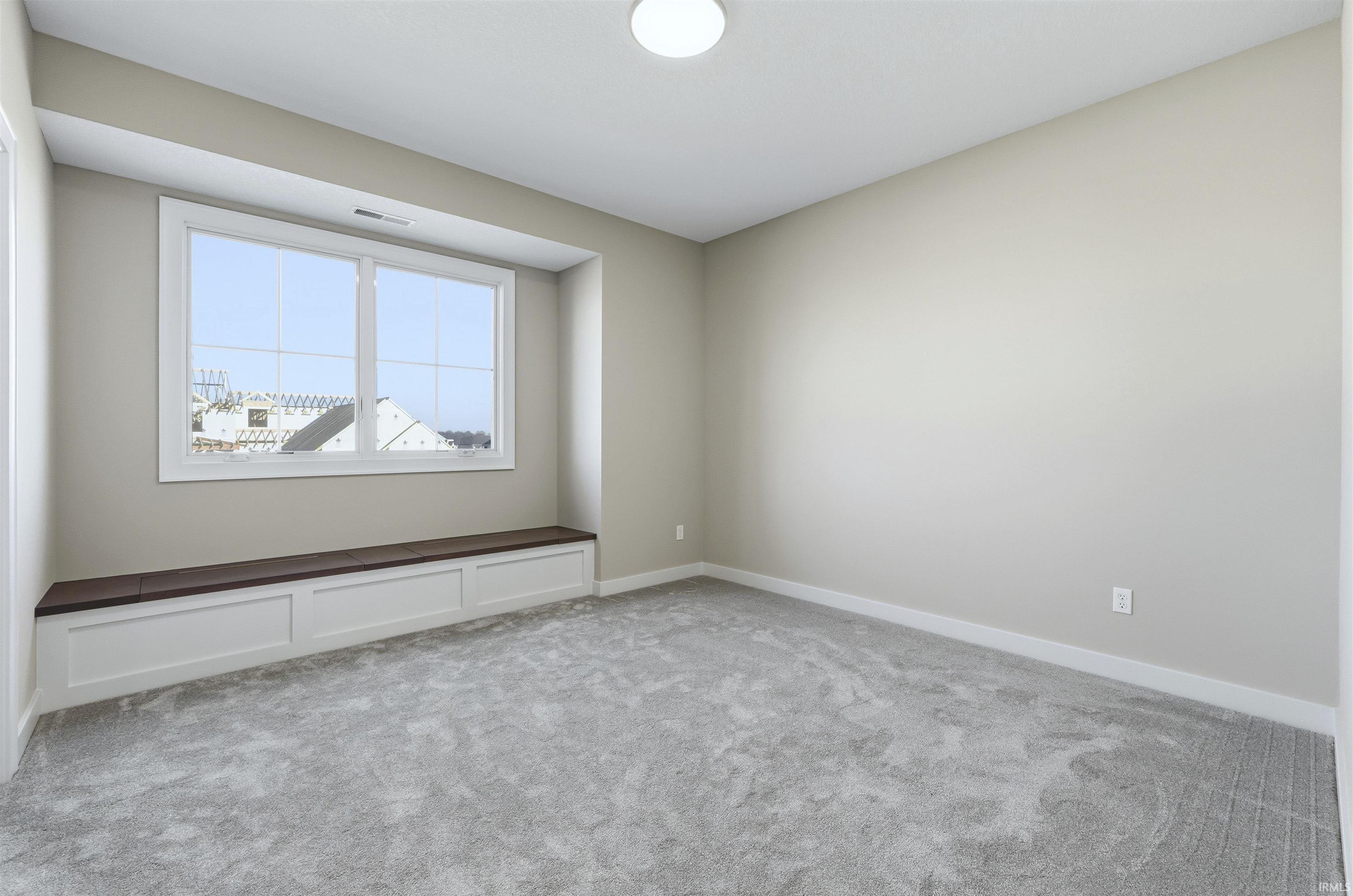 Empty room featuring light colored carpet and baseboards