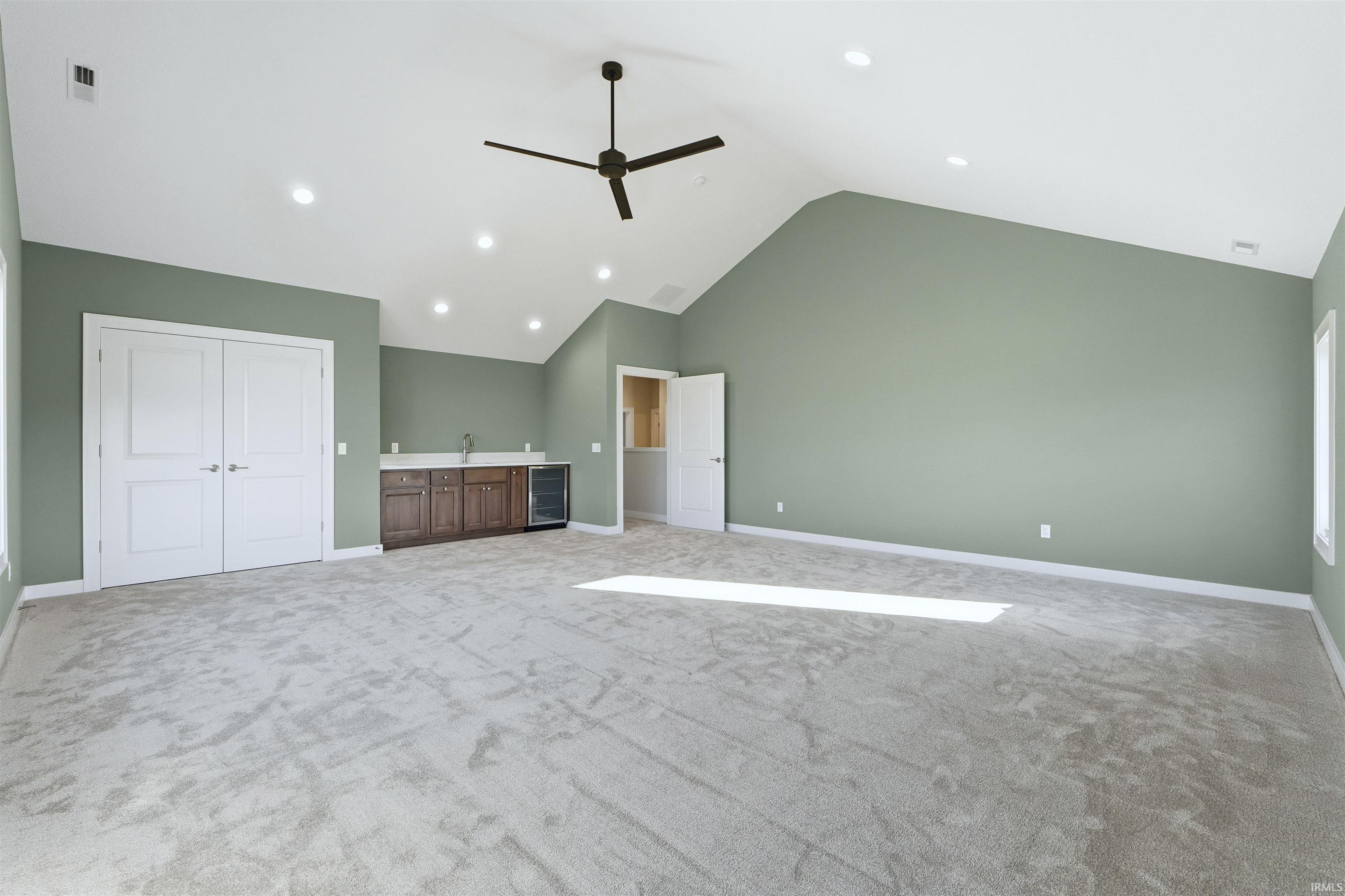 Unfurnished bedroom featuring ceiling fan, beverage cooler, high vaulted ceiling, recessed lighting, and light colored carpet