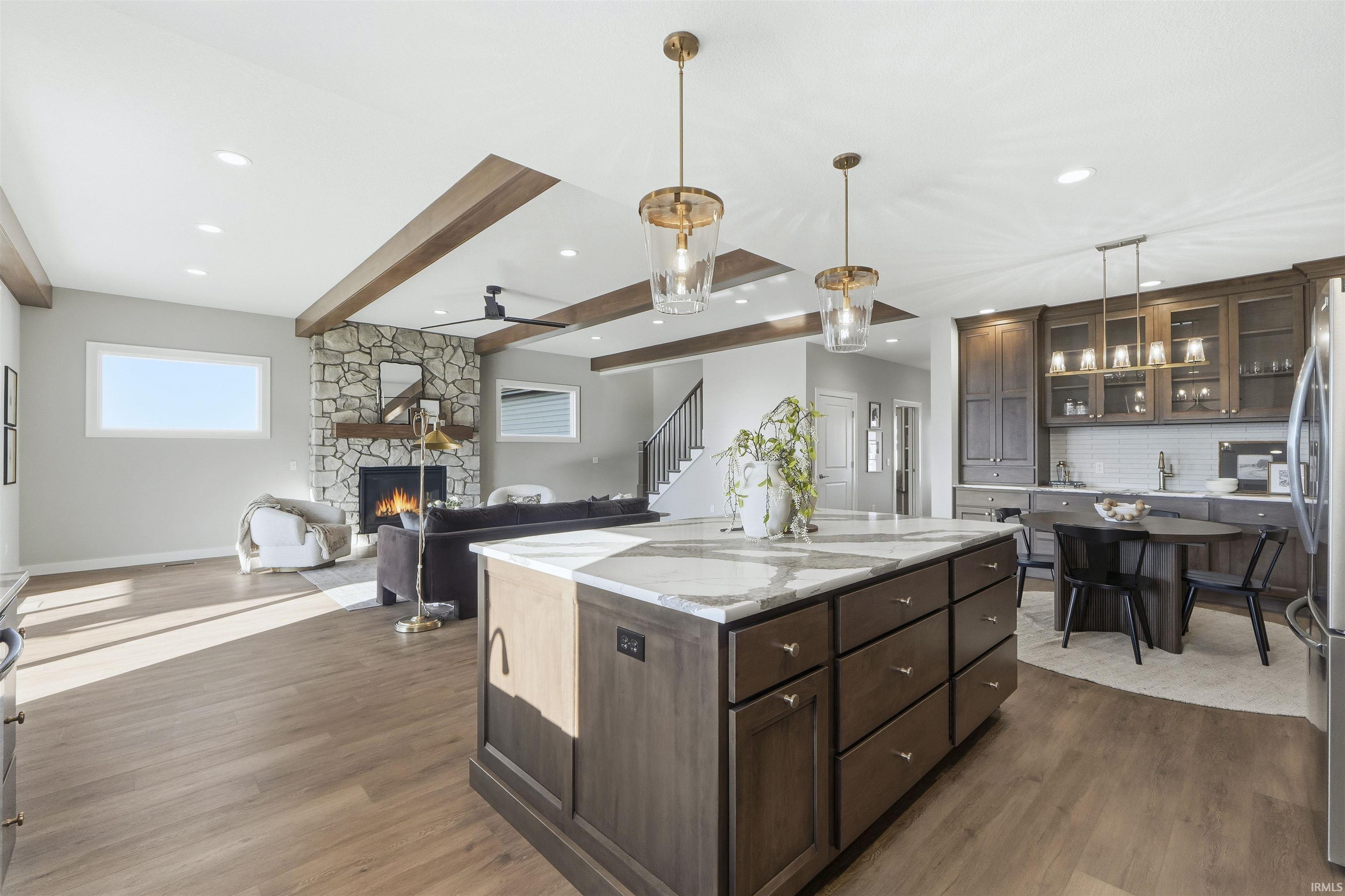 Kitchen featuring dark brown cabinetry, pendant lighting, glass insert cabinets, dark wood-type flooring, and light stone countertops