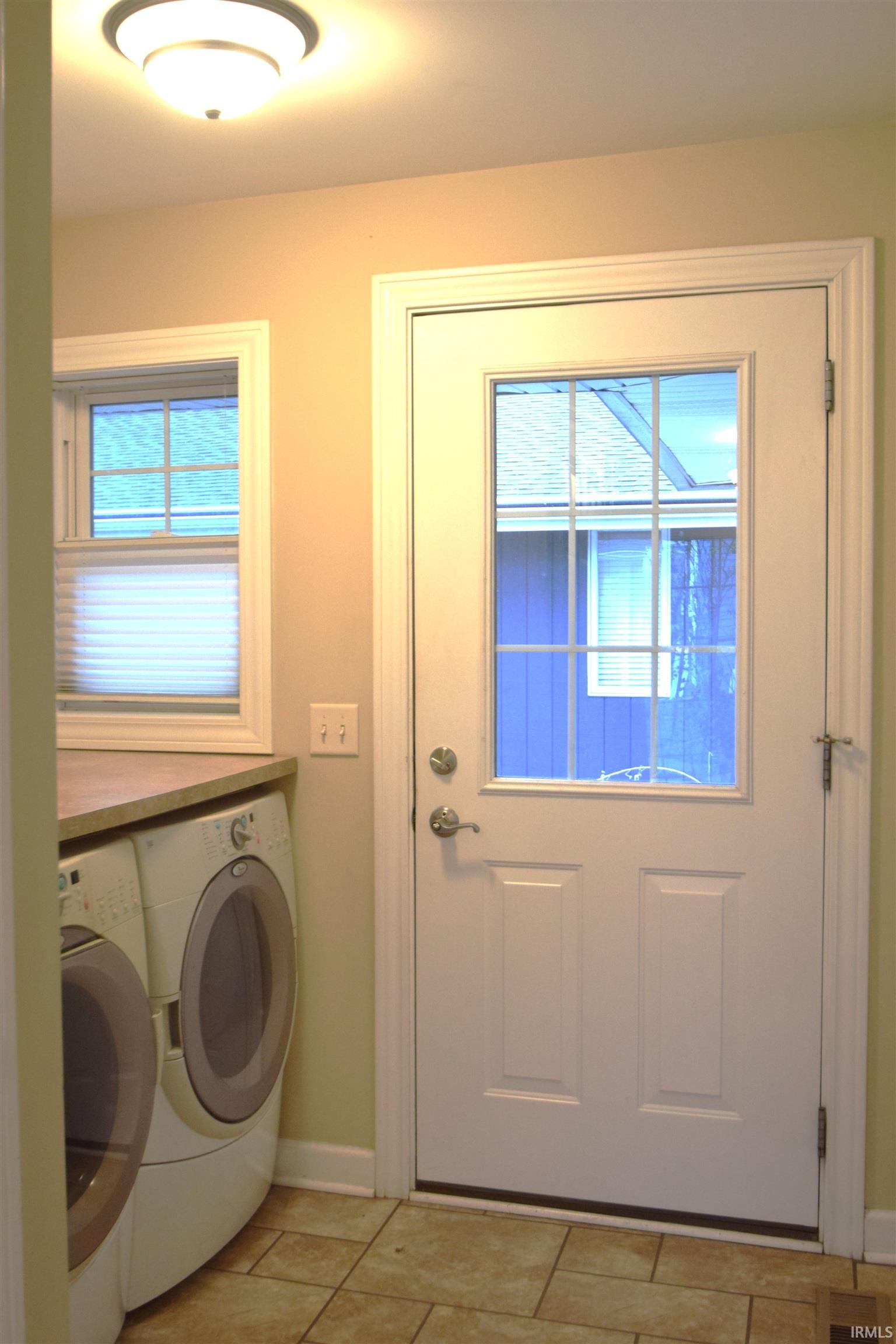 Laundry area featuring independent washer and dryer and light tile patterned floors