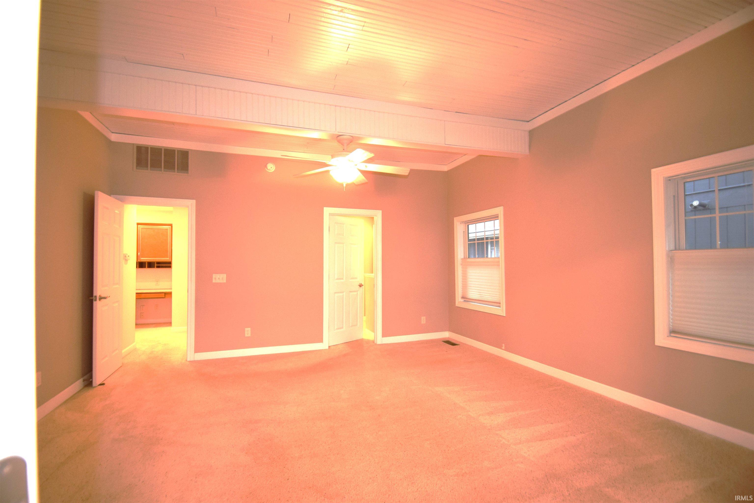 Carpeted empty room featuring a ceiling fan and wooden ceiling