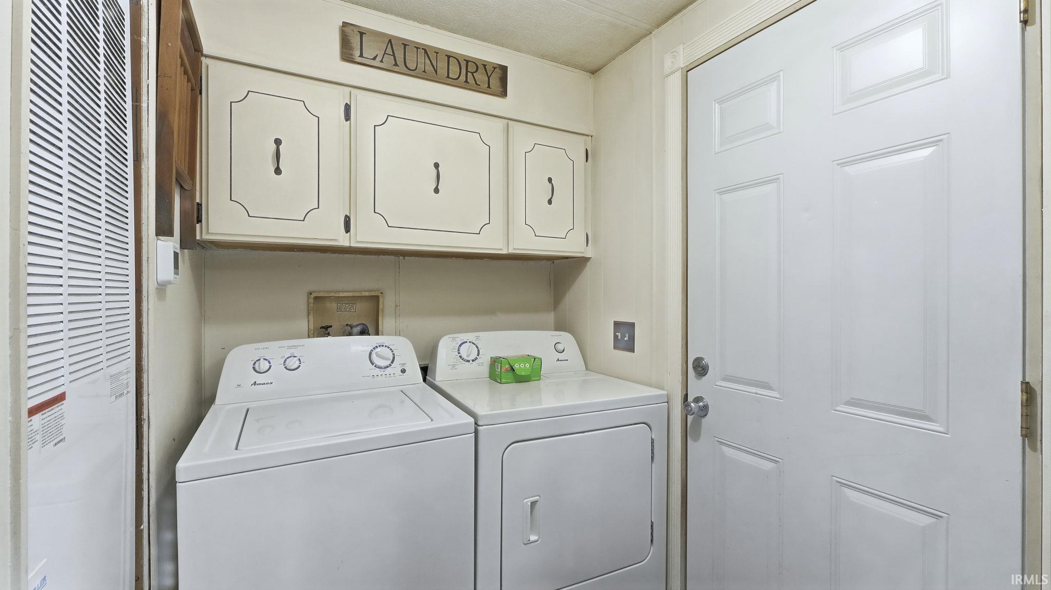 Laundry area featuring cabinet space, a heating unit, and washing machine and dryer