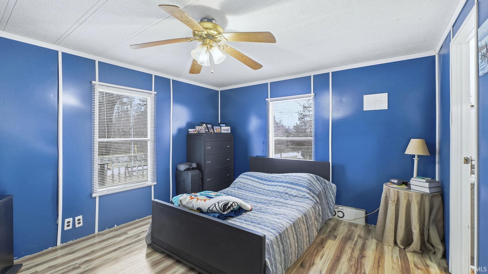 Bedroom with wood finished floors, ceiling fan, crown molding, and a textured ceiling