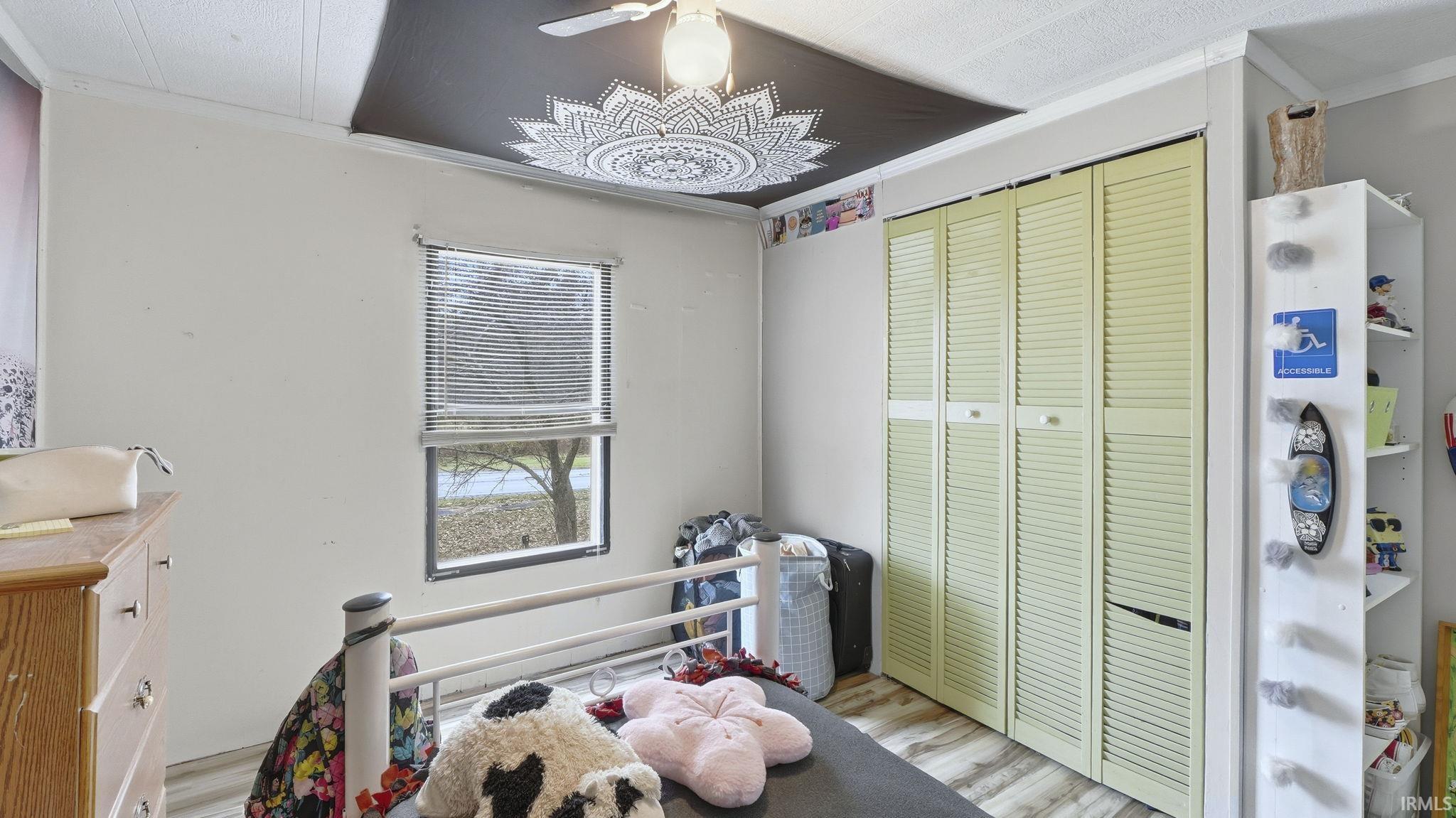 Bedroom featuring crown molding, wood finished floors, and a closet