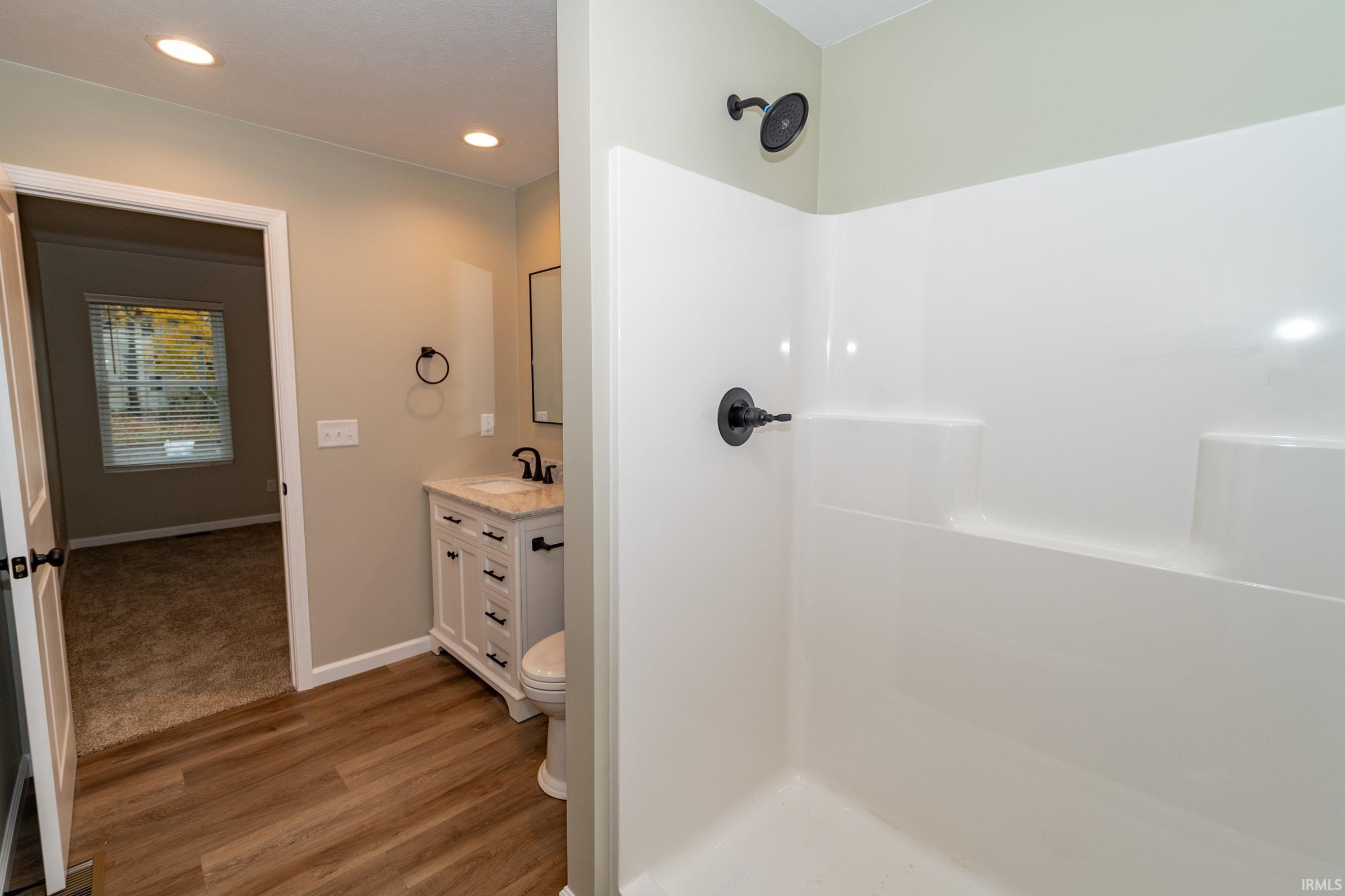Bathroom with vanity, a shower, recessed lighting, and light wood-style floors