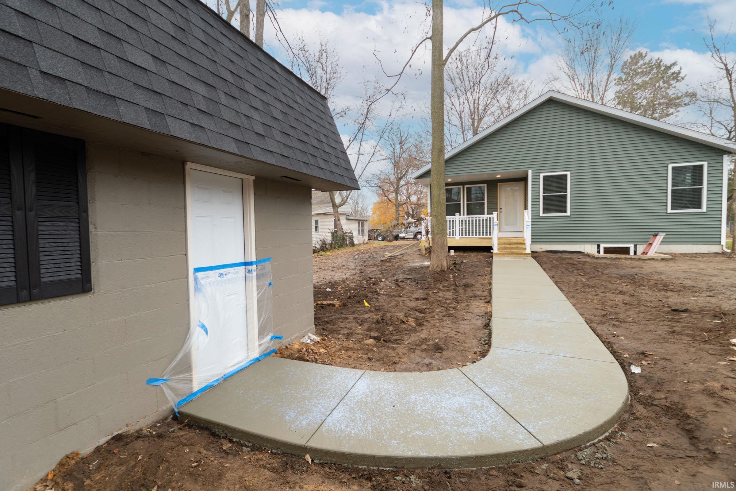 View of side of home with covered porch and roof with shingles