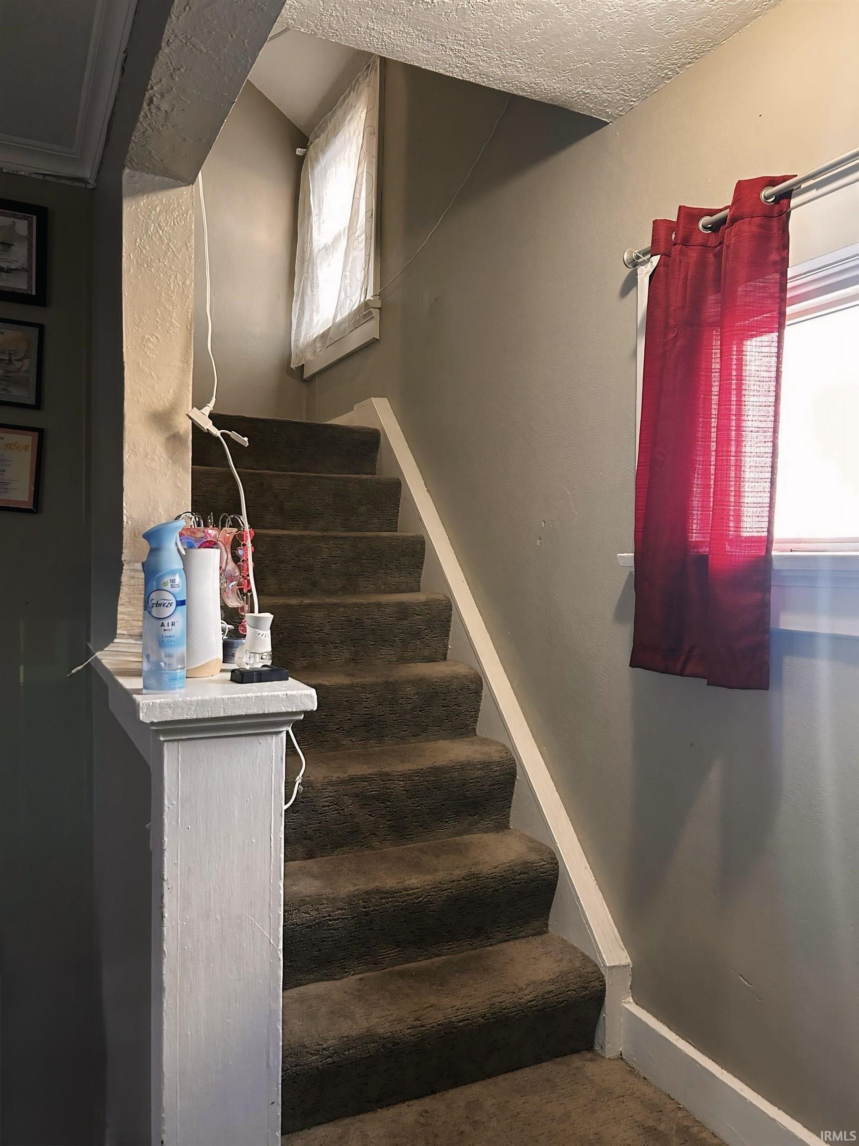 Stairs featuring baseboards and a textured ceiling