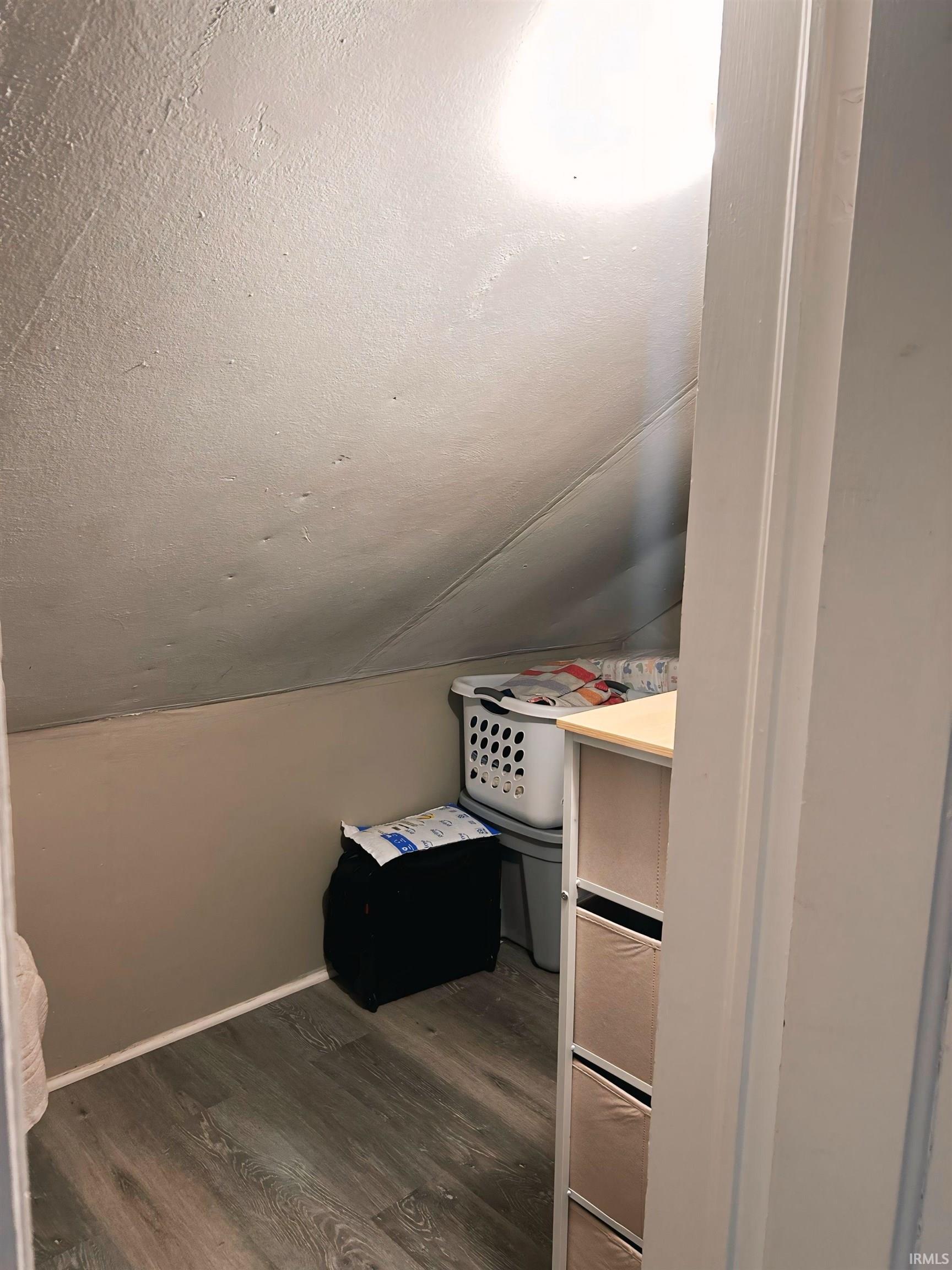 Additional living space featuring a textured ceiling, dark wood finished floors, and vaulted ceiling