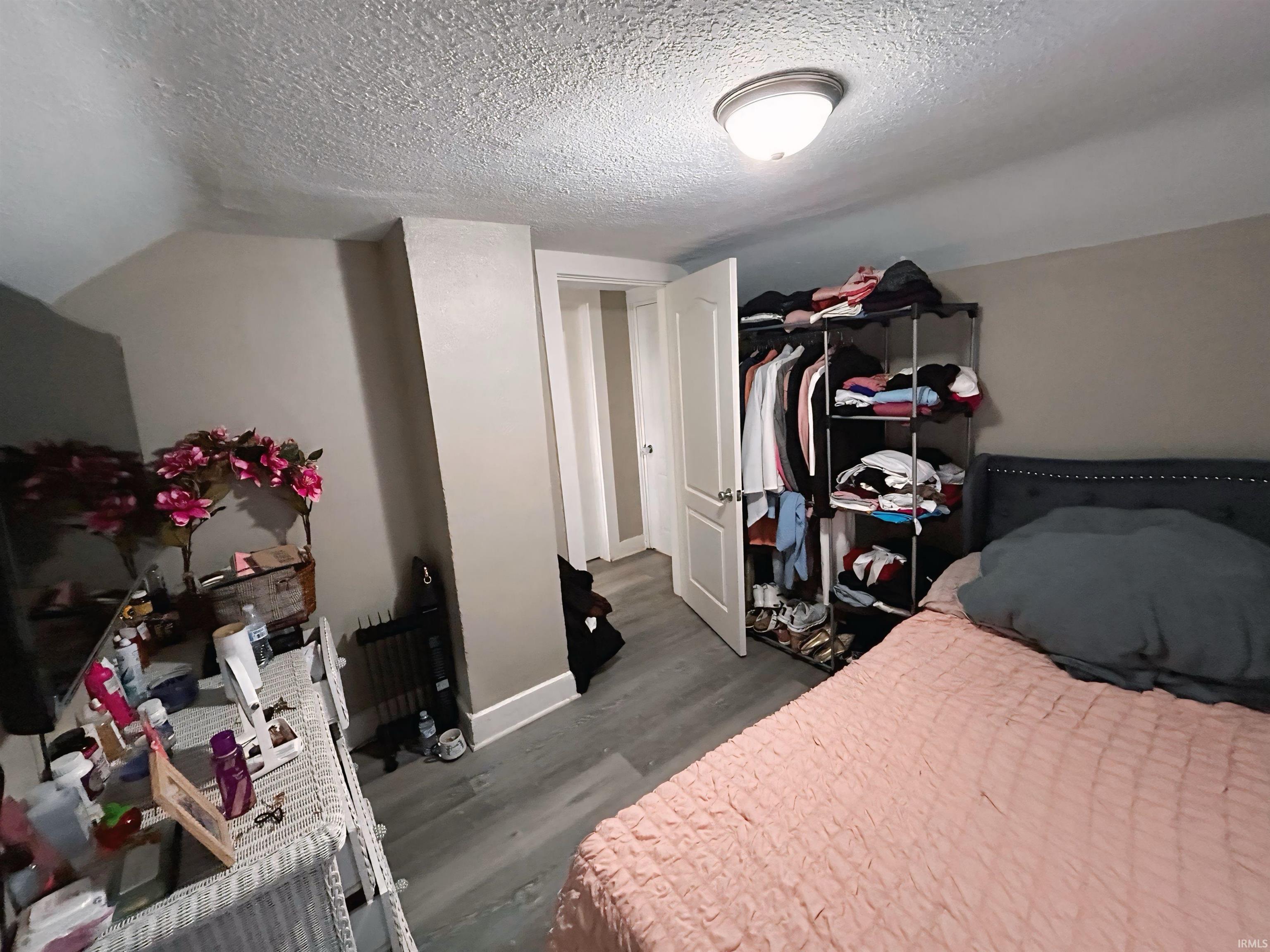 Bedroom featuring a textured ceiling, dark wood-style flooring, lofted ceiling, and a closet