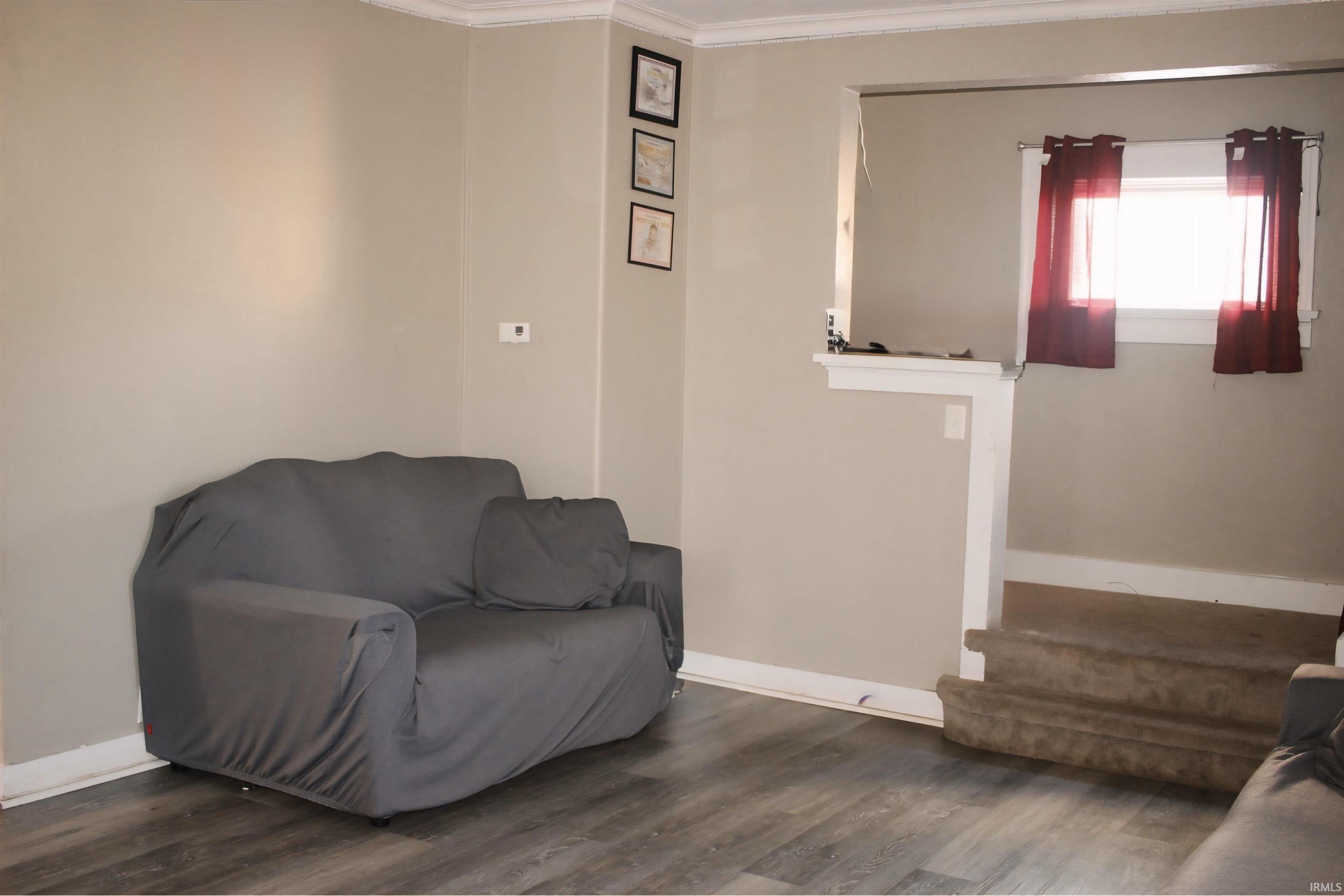 Living area featuring dark wood-style floors and ornamental molding