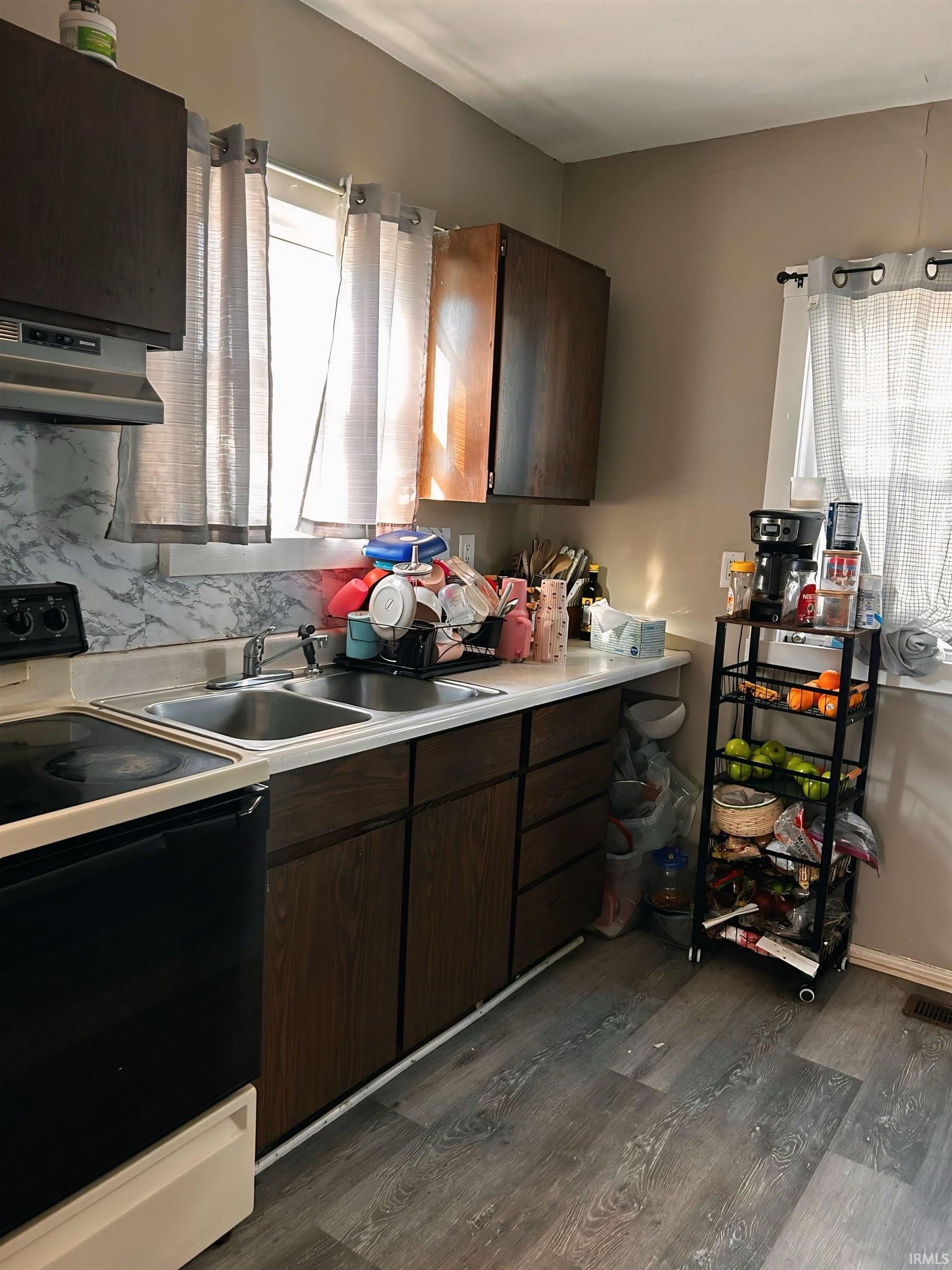 Kitchen with range with electric stovetop, dark brown cabinets, light countertops, wall chimney exhaust hood, and dark wood-style flooring