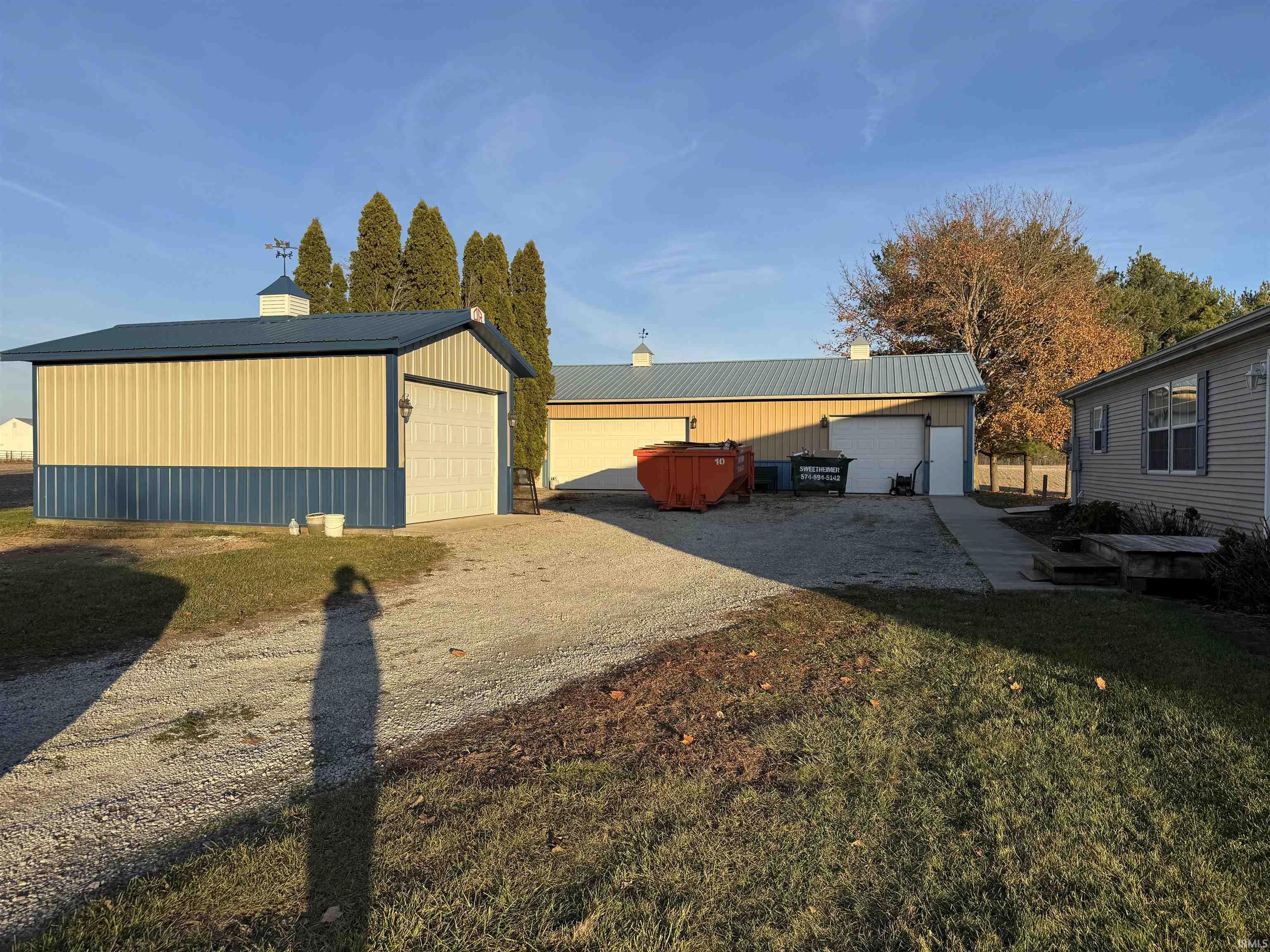 Exterior space with a garage, an outbuilding, a chimney, and a metal roof