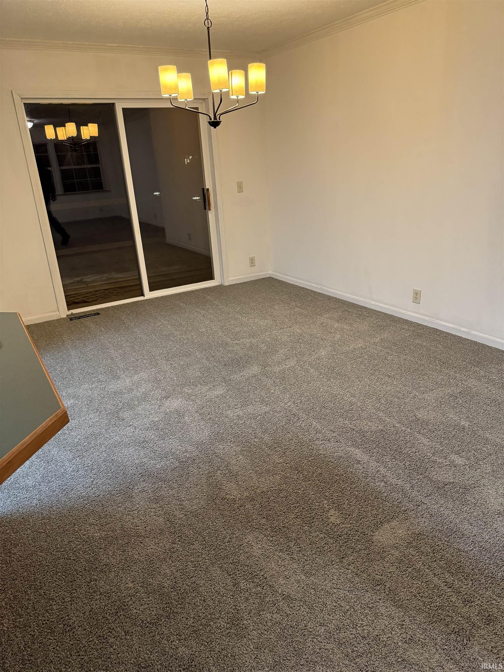 Dining room with dark colored carpet, crown molding, a chandelier, and a textured ceiling