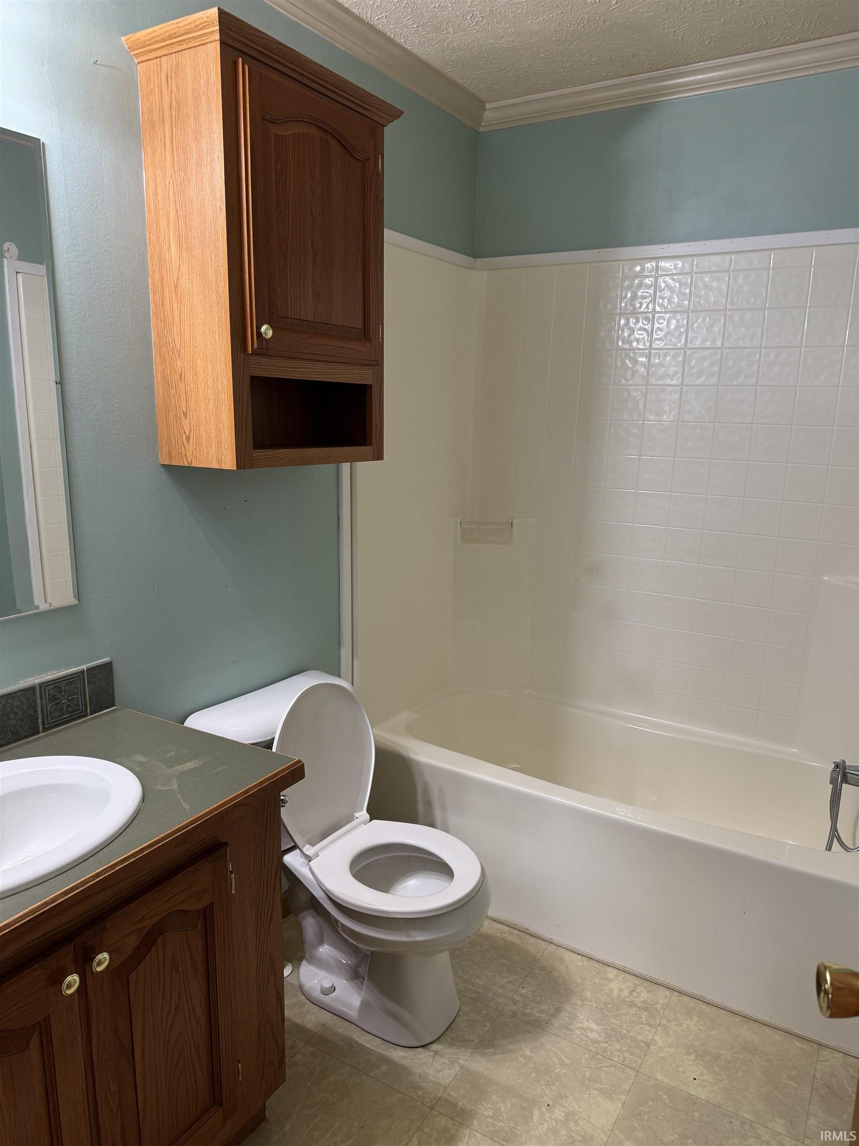 Bathroom with a textured ceiling, vanity, and ornamental molding