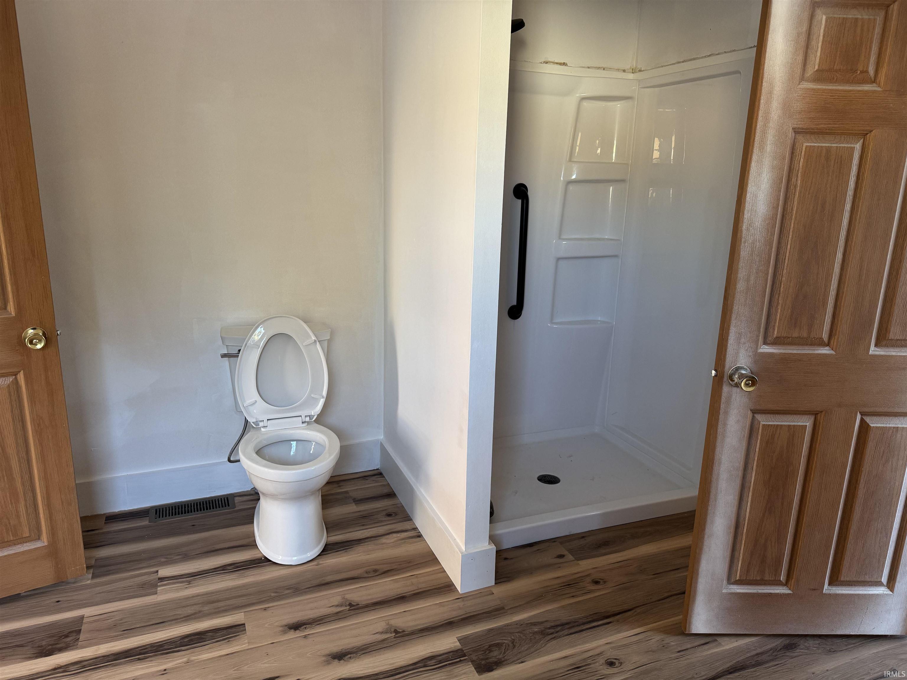 Full bath featuring a shower stall and wood finished floors