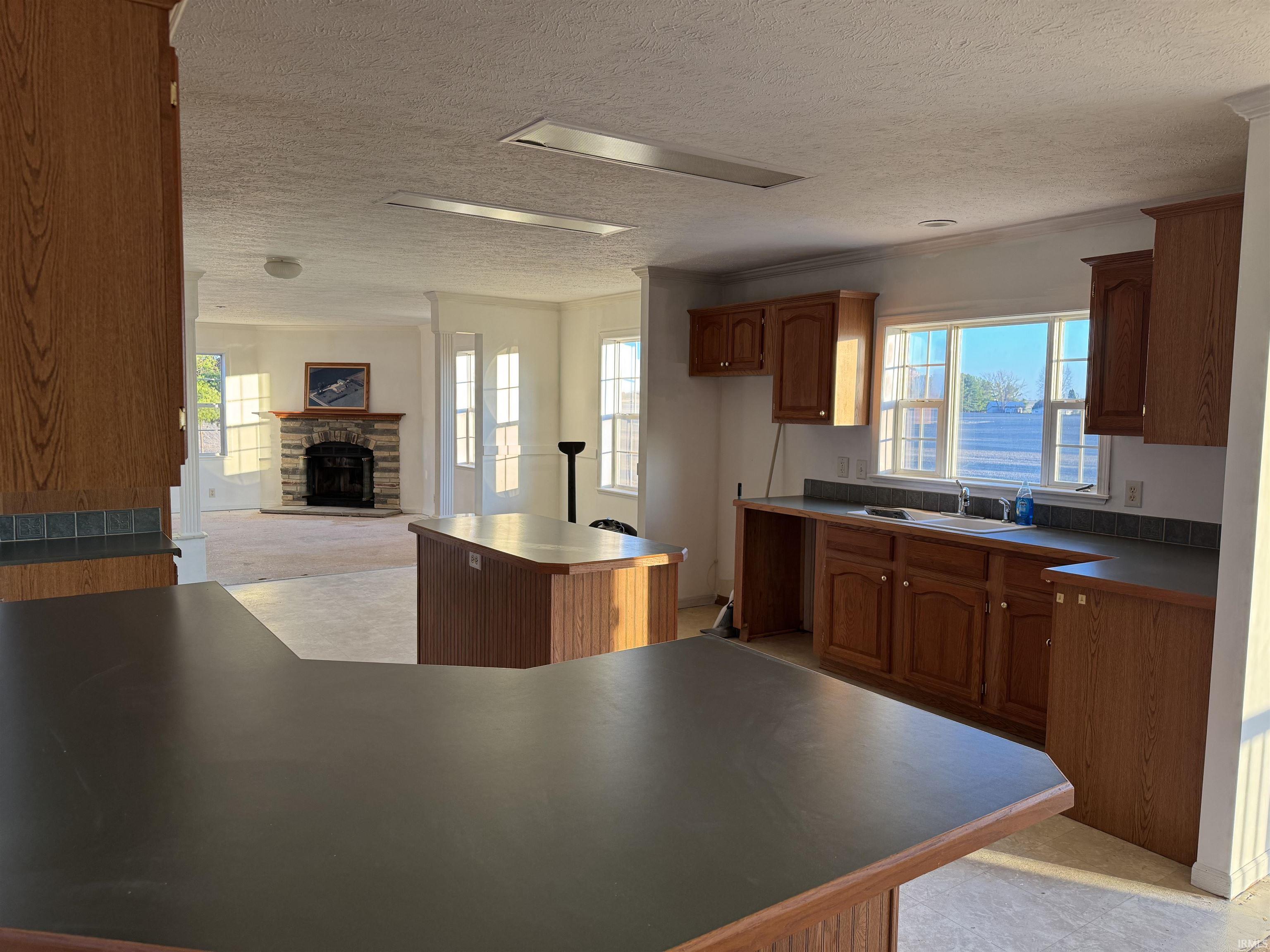 Kitchen featuring brown cabinets, a center island, plenty of natural light, and a textured ceiling
